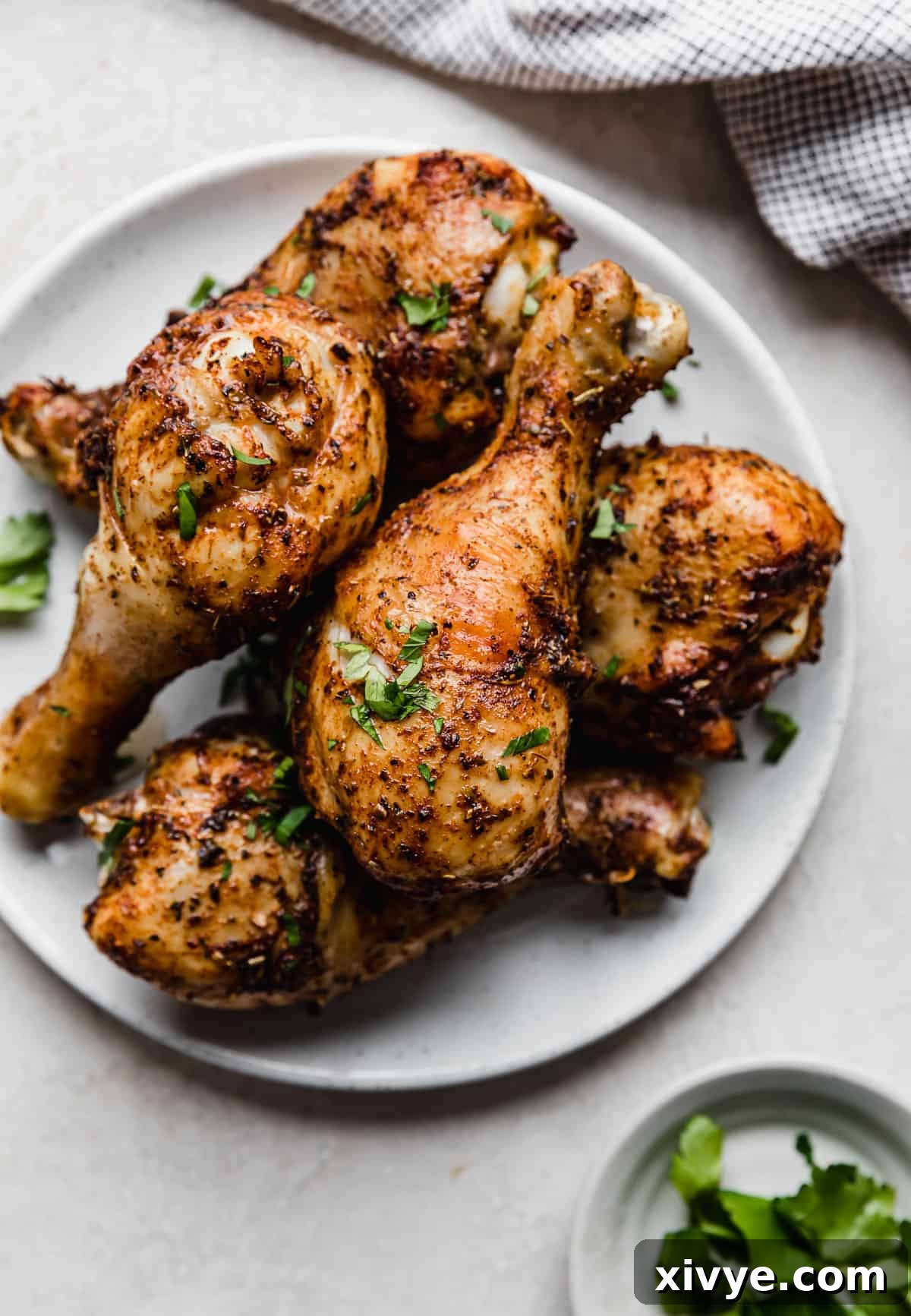 Crispy Air Fryer Drumsticks 2 Golden crispy Air Fryer Chicken Legs on a white plate on a white textured background.