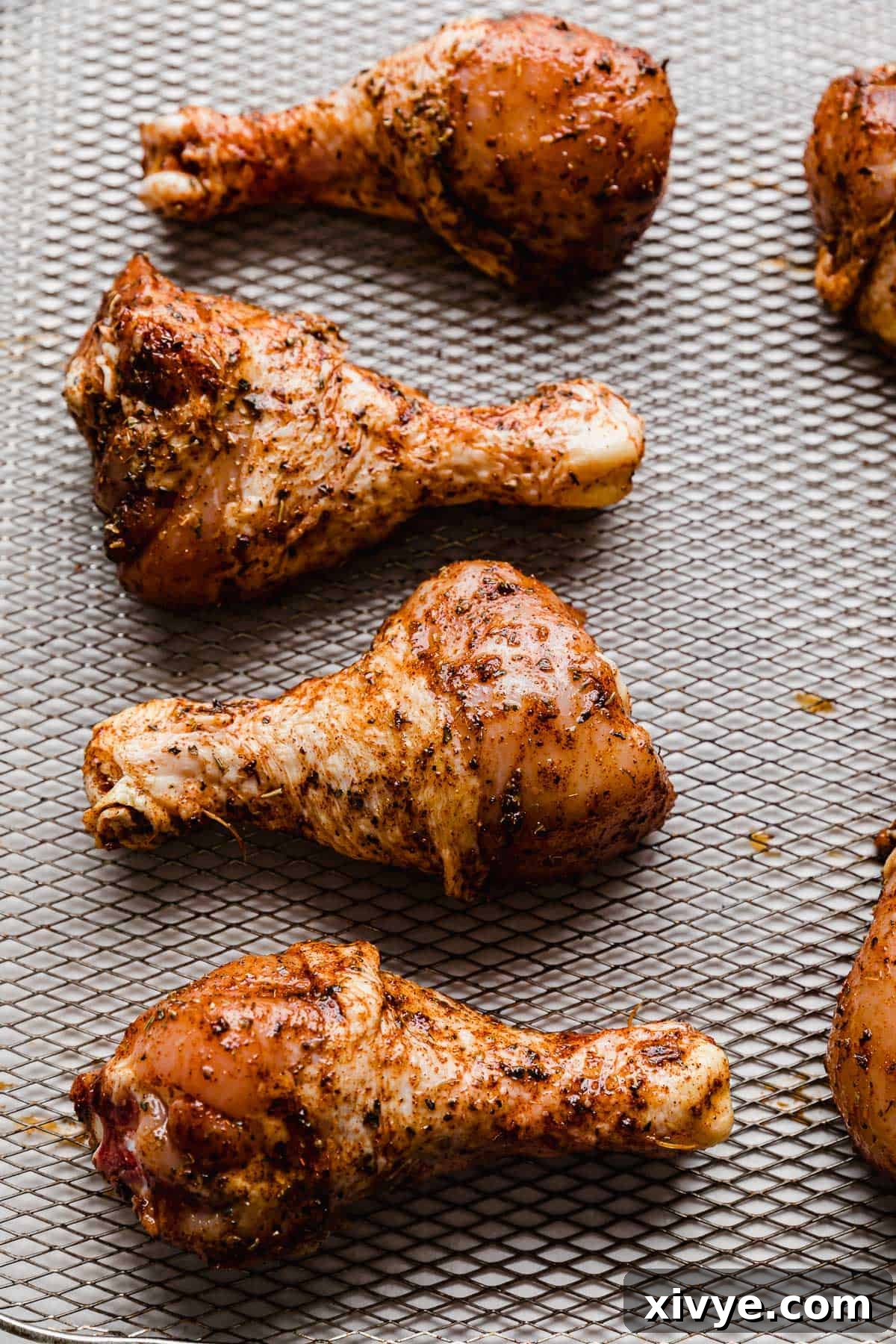 Crispy Air Fryer Drumsticks 7 Seasoned chicken legs on an air fryer basket.