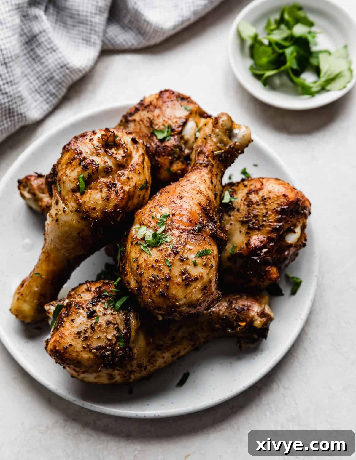 Crispy Air Fryer Drumsticks 9 Golden and crispy Air Fryer Chicken Legs on a white plate garnished with fresh parsley.