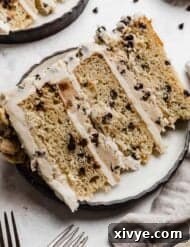 A three layer mini chocolate chip Cookie Dough Cake on a white plate against a white background.
