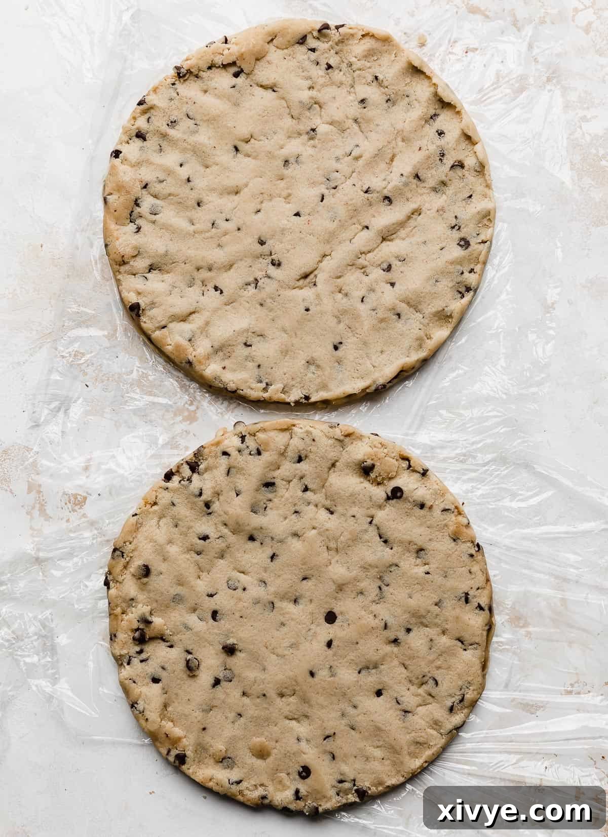 Two round disks of edible cookie dough on a white background.