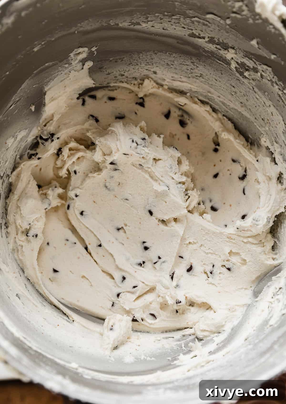 Close up photo of white frosting that has mini chocolate chips mixed into it.