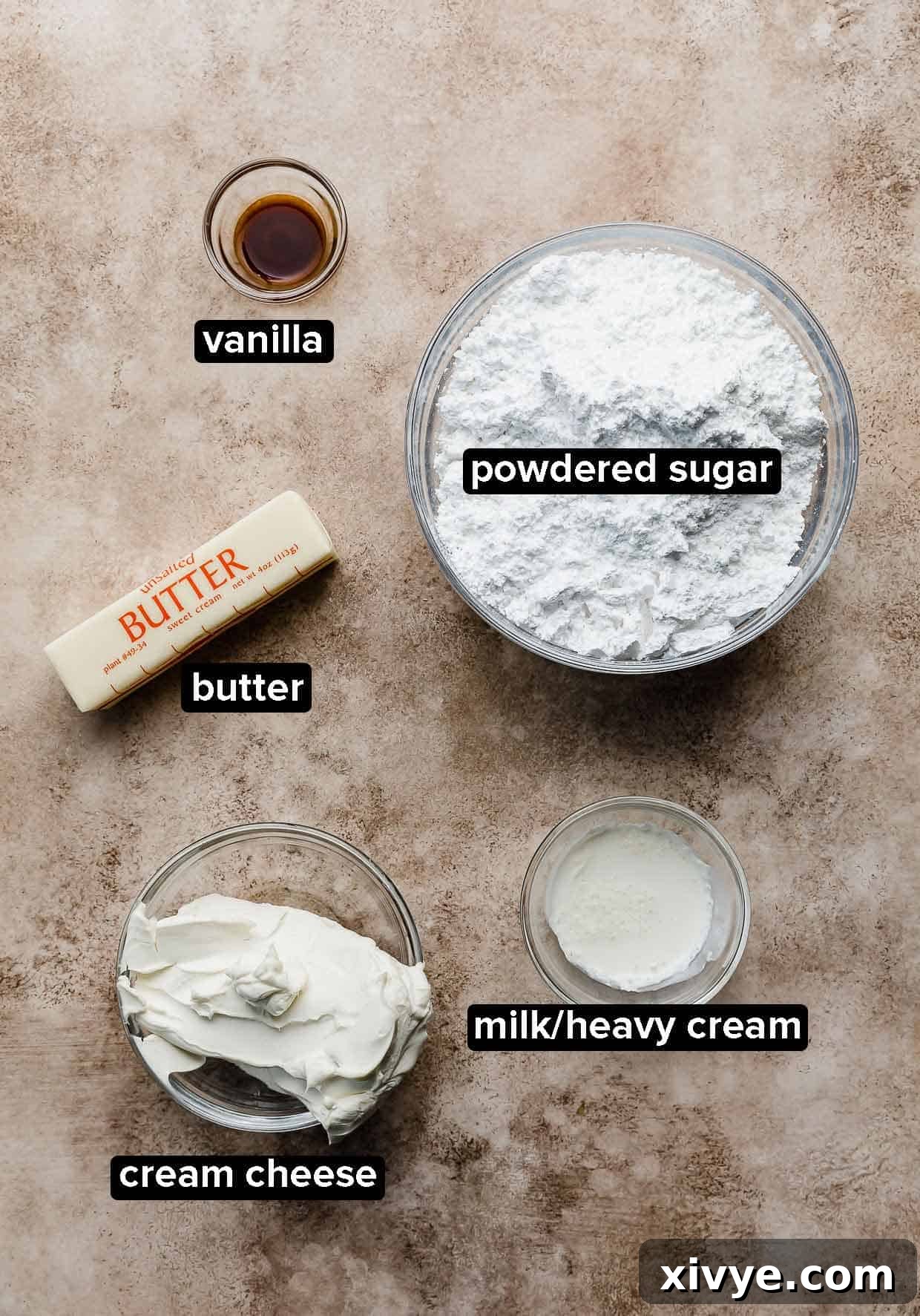 Cream cheese frosting ingredients on a light brown background, that'll be used to top a Libby's pumpkin sheet cake recipe.