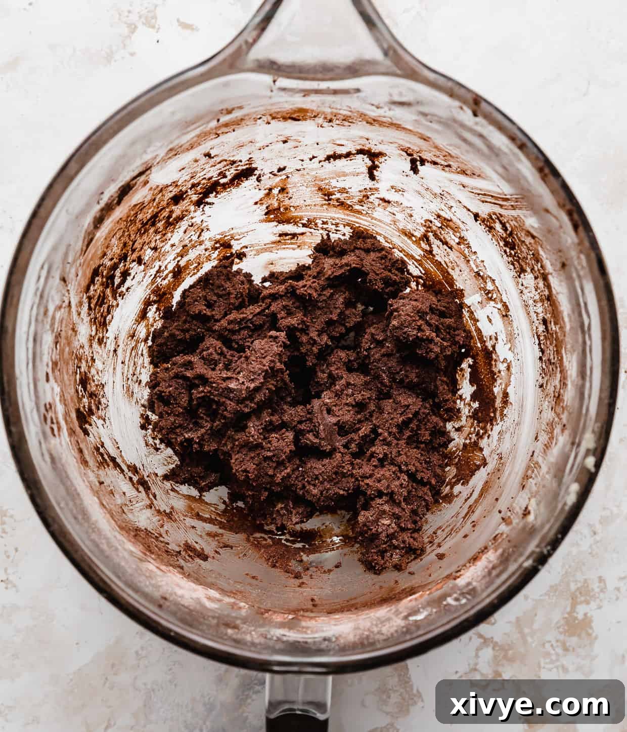 Decadent Mint Brownie Cookie Bliss 4 Rich chocolate cookie dough in a clear glass mixing bowl, showcasing its dark, smooth texture.