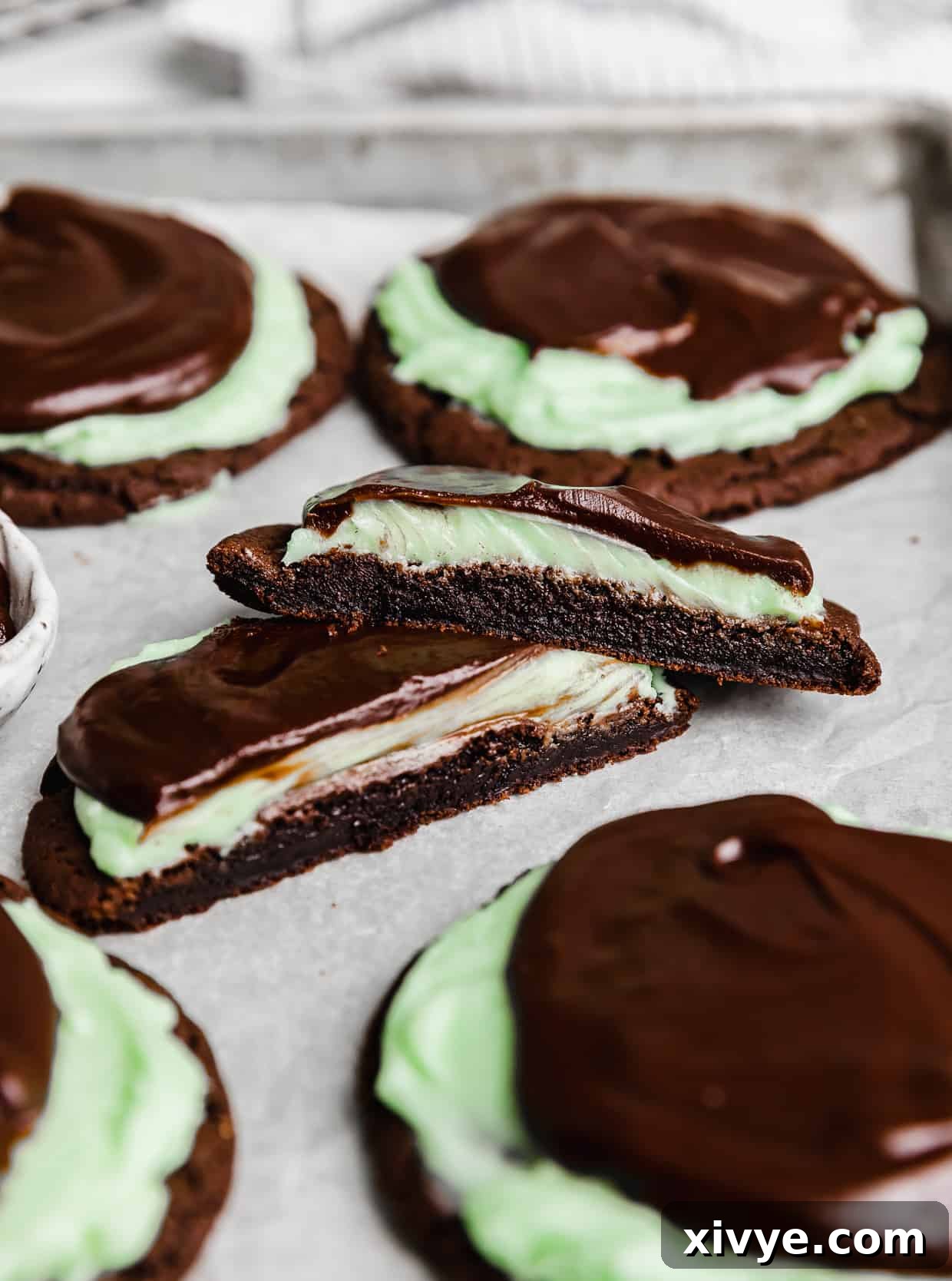 Decadent Mint Brownie Cookie Bliss 10 A Copycat Crumbl Mint Brownie Cookie cut in half, revealing its moist chocolate base, fluffy mint frosting, and rich chocolate ganache layers.