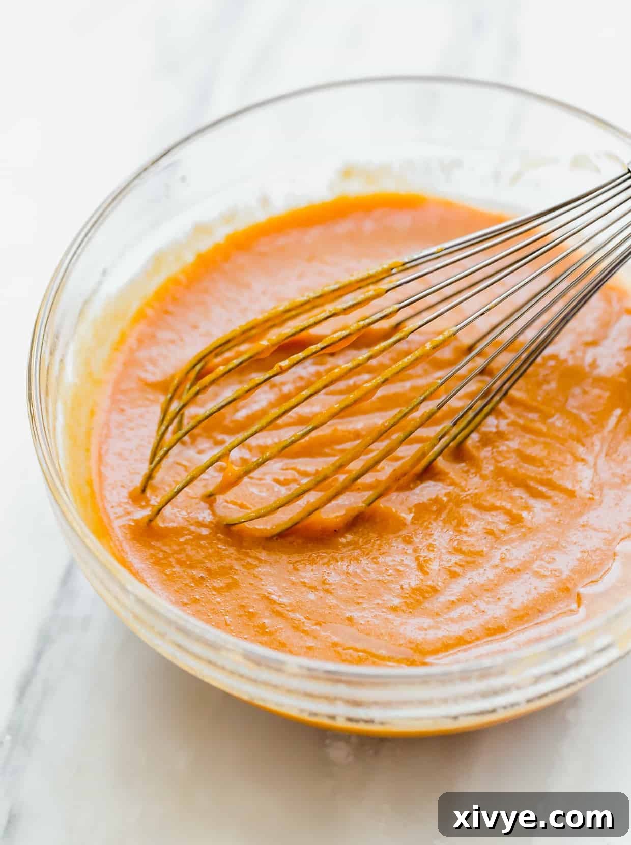 Spiced Pumpkin Chocolate Chip Bread 5 A whisk in a glass bowl stirring pumpkin puree and the wet ingredients for making pumpkin bread.