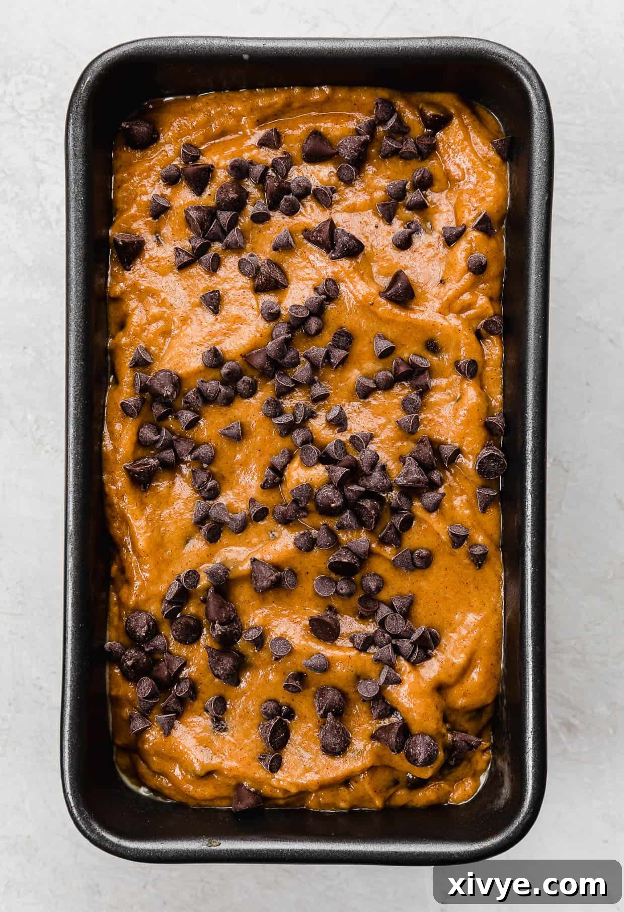 Spiced Pumpkin Chocolate Chip Bread 6 Unbaked Pumpkin Chocolate Chip Bread in a loaf pan topped with mini chocolate chips and semi-sweet chocolate chips, ready for the oven.