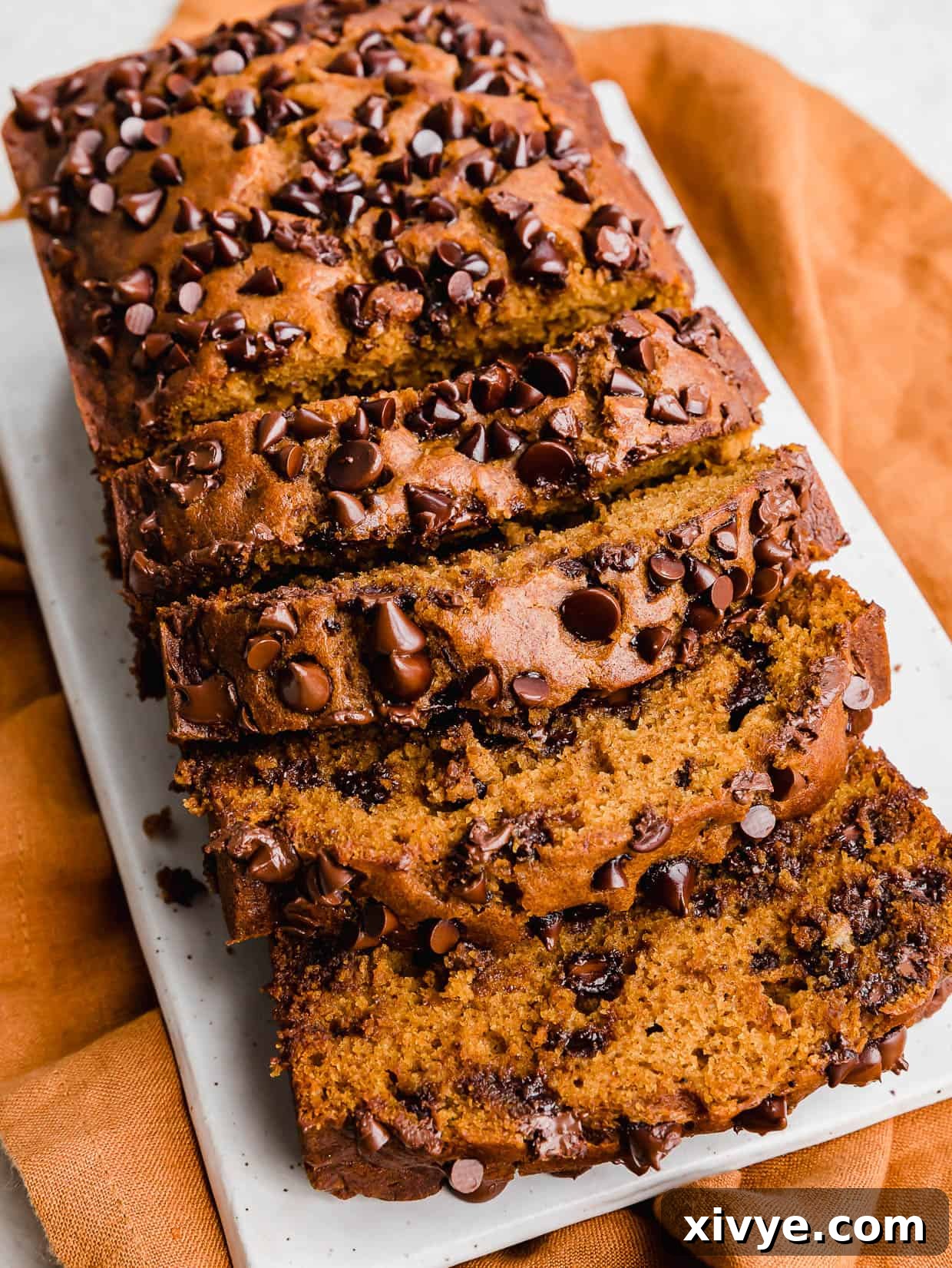 Spiced Pumpkin Chocolate Chip Bread 8 Pumpkin Chocolate Chip Bread sliced, on a white rectangular plate, ready to be served.