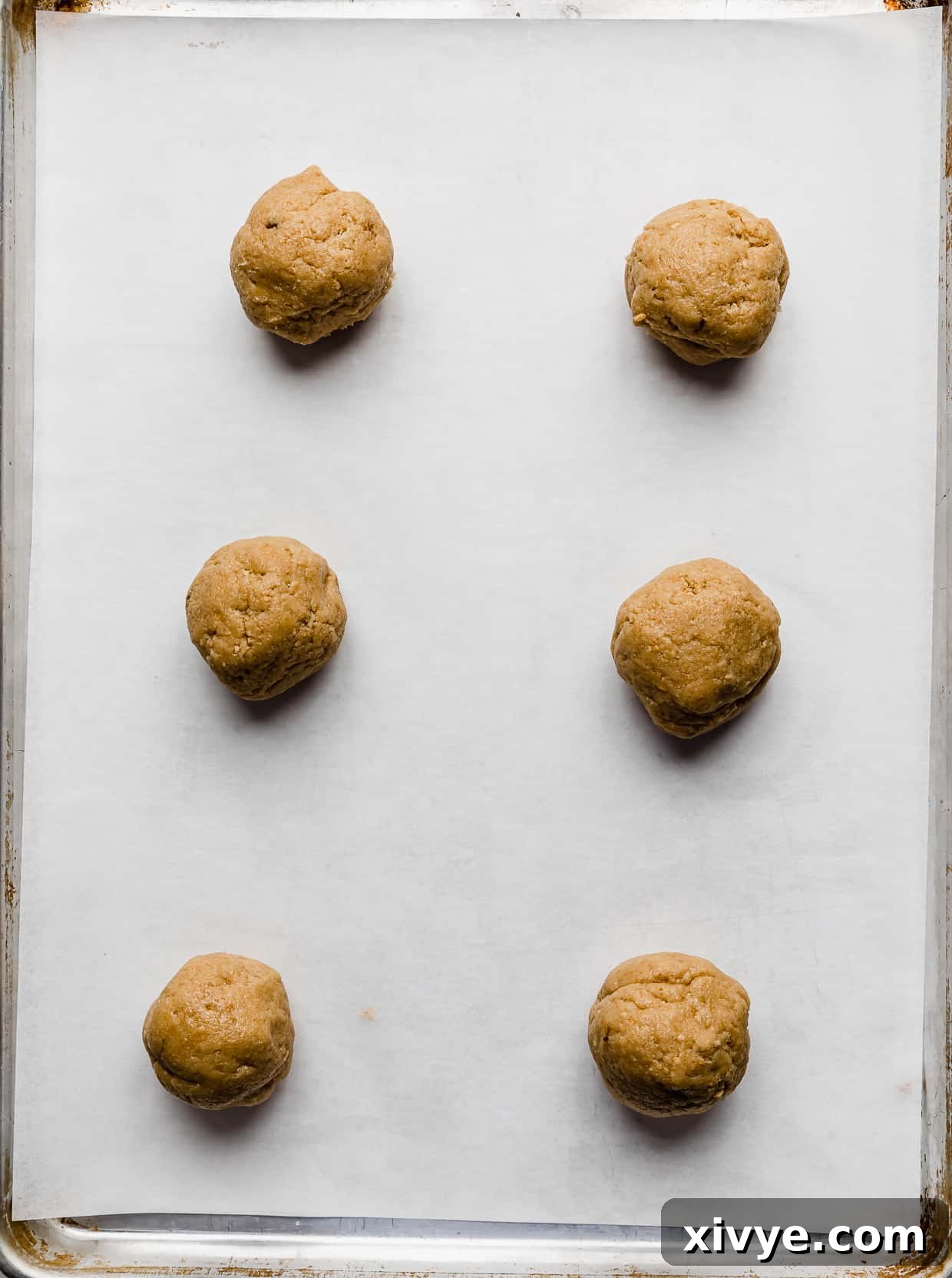 Tangy Key Lime Cookie Delight 5 Six tan cookie dough balls on a white parchment lined baking sheet.