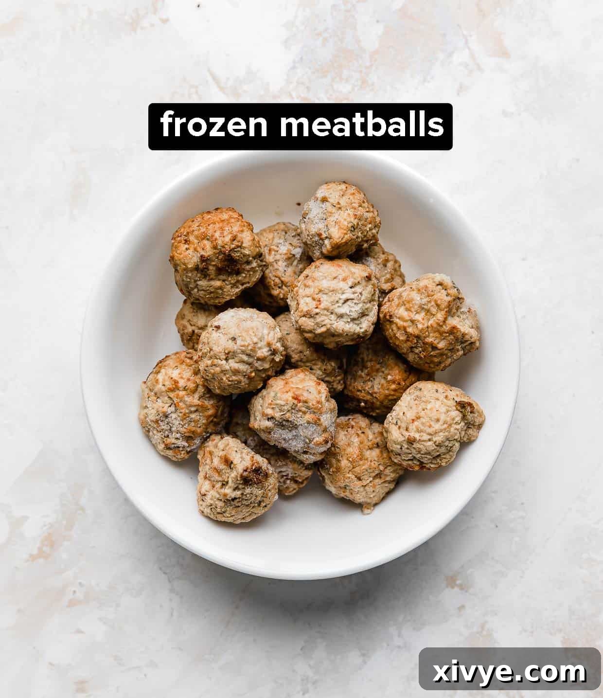 A white bowl with frozen meatballs in it.