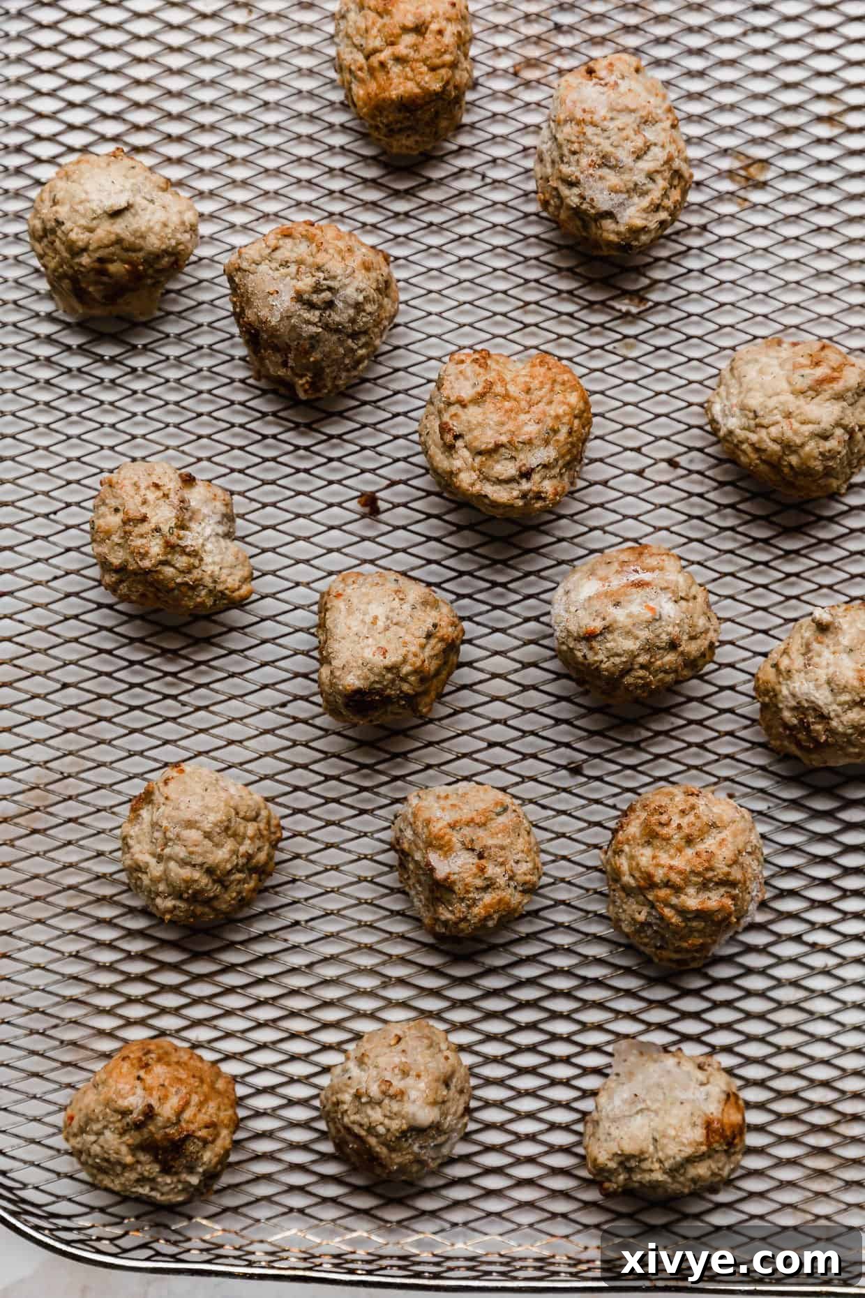 Frozen meatballs on a wire air fryer basket.