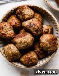 Meatballs cooked in the air fryer in a ceramic bowl on a white background.