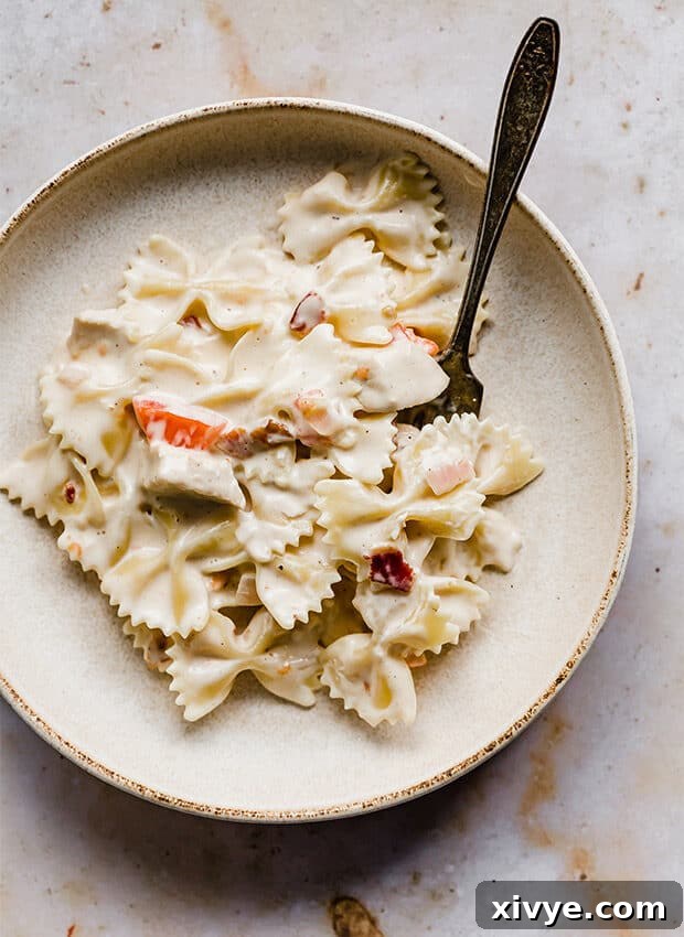 A pasta plate, against a beige background, full of Johnny Carinos Bowtie Festival pasta.