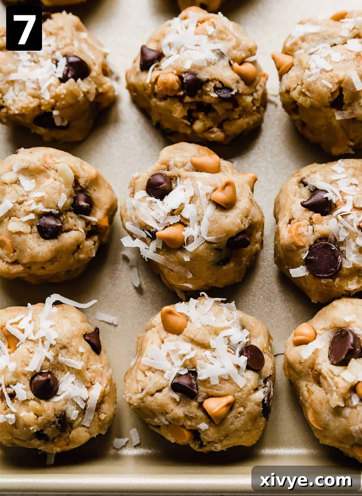 Irresistible Seven-Layer Bars 6 7 Layer Bar Cookie dough balls with shredded coconut and butterscotch and chocolate chips on the tops of the dough.