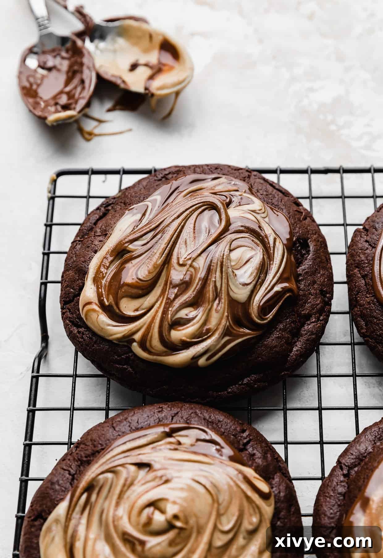 Fudgy Peanut Butter Brownie Cookies 12 Chocolate and peanut butter swirled on top of a brownie cookie on a wire cooling rack.