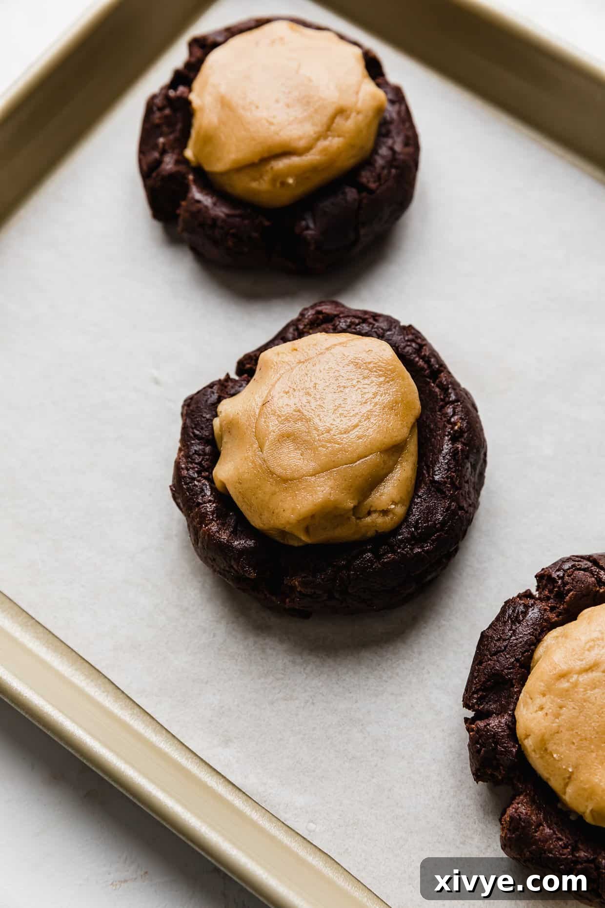 Fudgy Peanut Butter Brownie Cookies 6 A ball of peanut butter cookie dough on top of a brownie cookie dough ball.