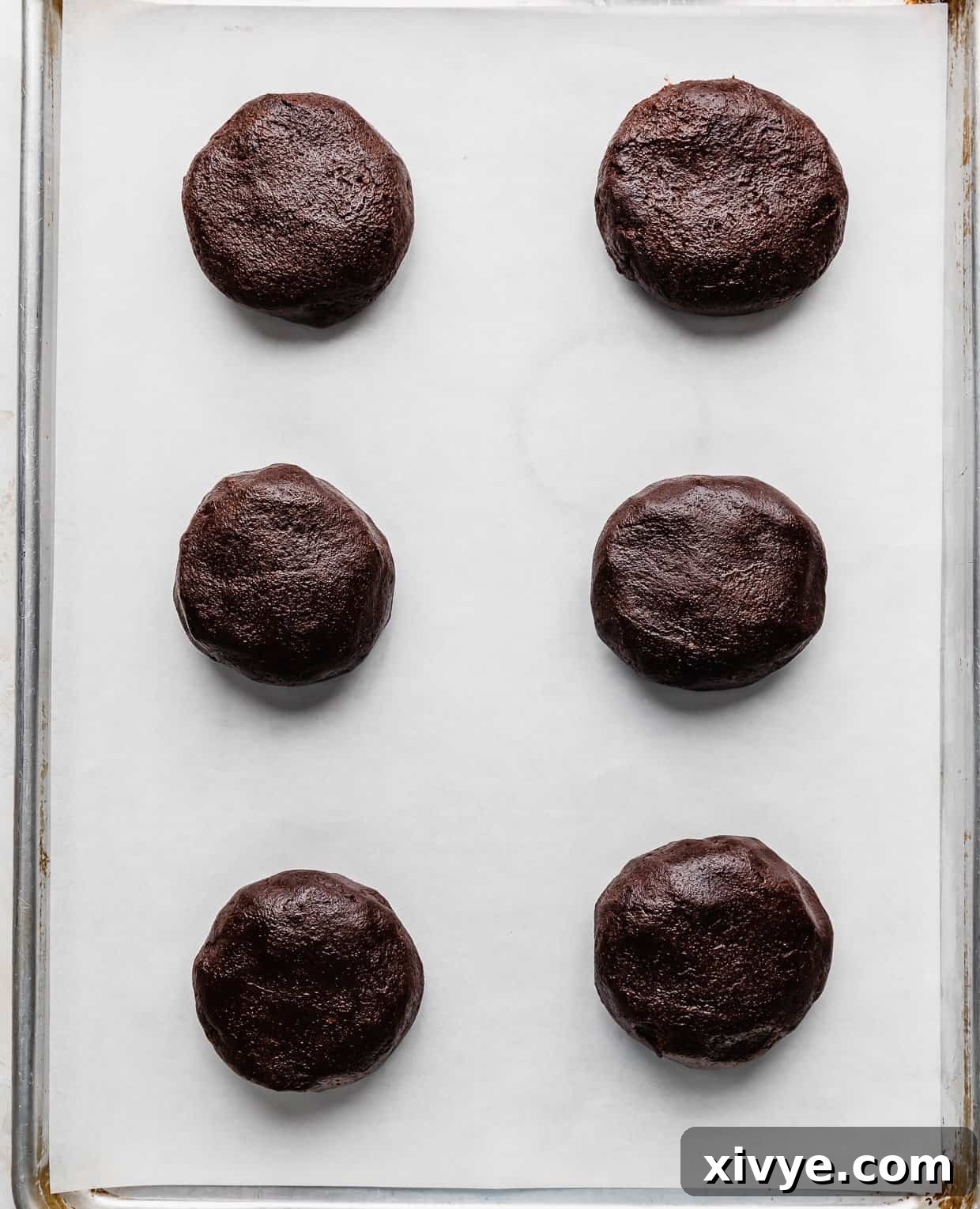 Fudgy Peanut Butter Brownie Cookies 8 Six Peanut Butter Brownie Cookie dough balls on a white parchment lined baking sheet.