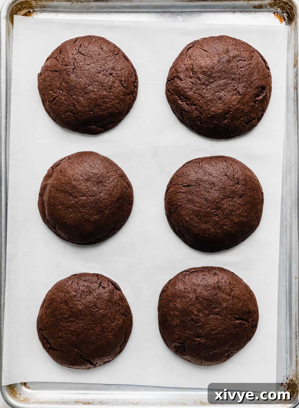 Fudgy Peanut Butter Brownie Cookies 9 Six baked brownie cookies on a white parchment paper.