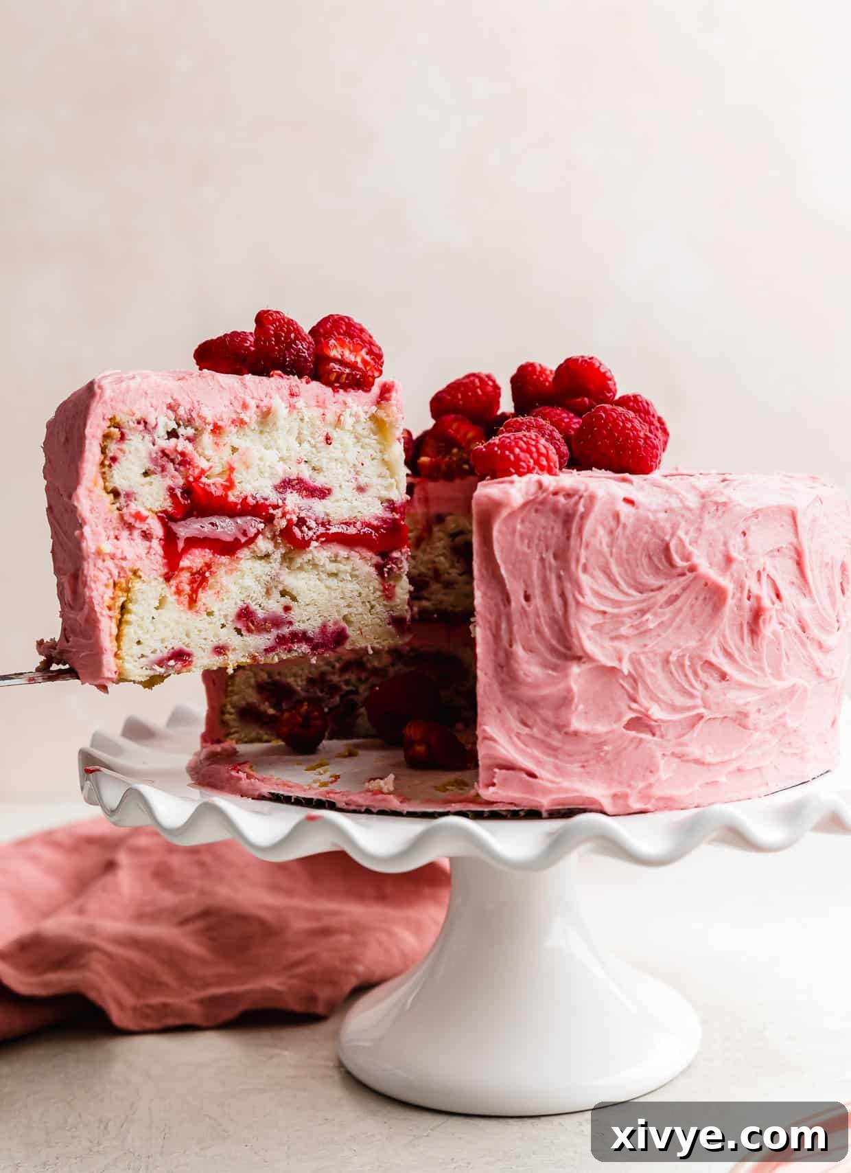 Zesty Lemon Raspberry Delight 2 A slice of fresh Lemon Raspberry layer cake on a knife being lifted from the full cake, showcasing the beautiful layers and filling.