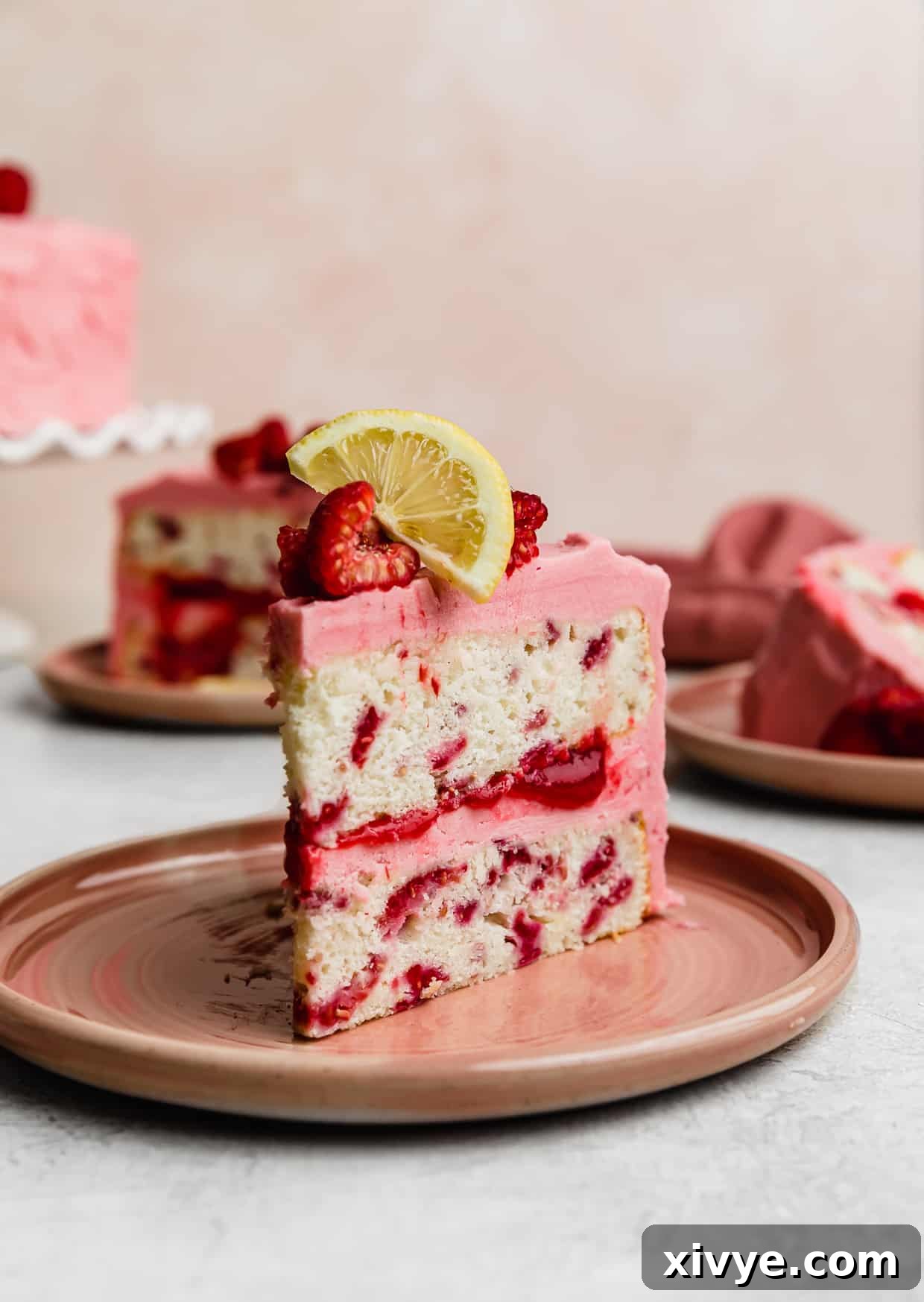Zesty Lemon Raspberry Delight 3 A slice of Lemon Raspberry Cake on a pink plate against a light pink background, showing the raspberry filling.