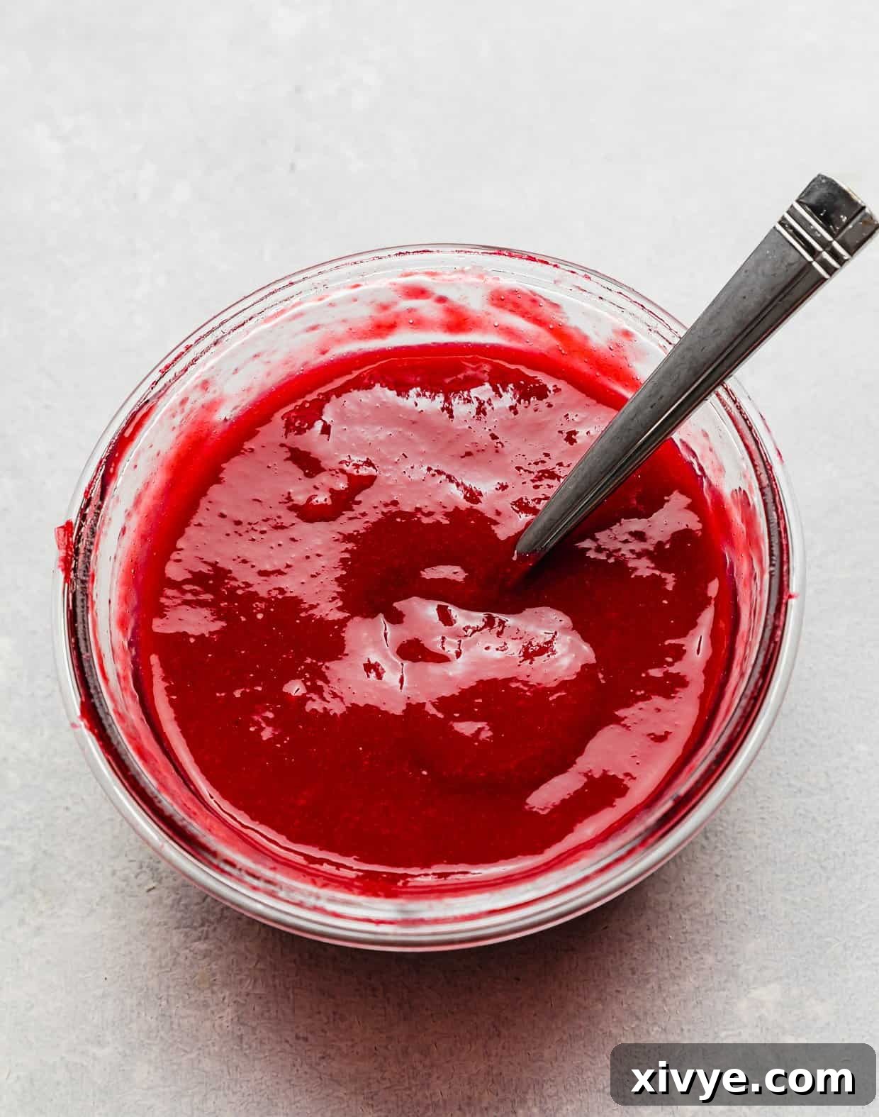 Zesty Lemon Raspberry Delight 5 A clear glass bowl showcasing a vibrant homemade raspberry sauce, perfectly smooth and ready for filling.