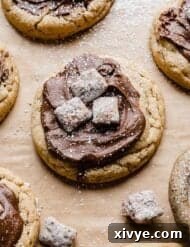 A Crumbl Muddy Buddy Cookie topped with melted chocolate and muddy buddy pieces, ready to be enjoyed.