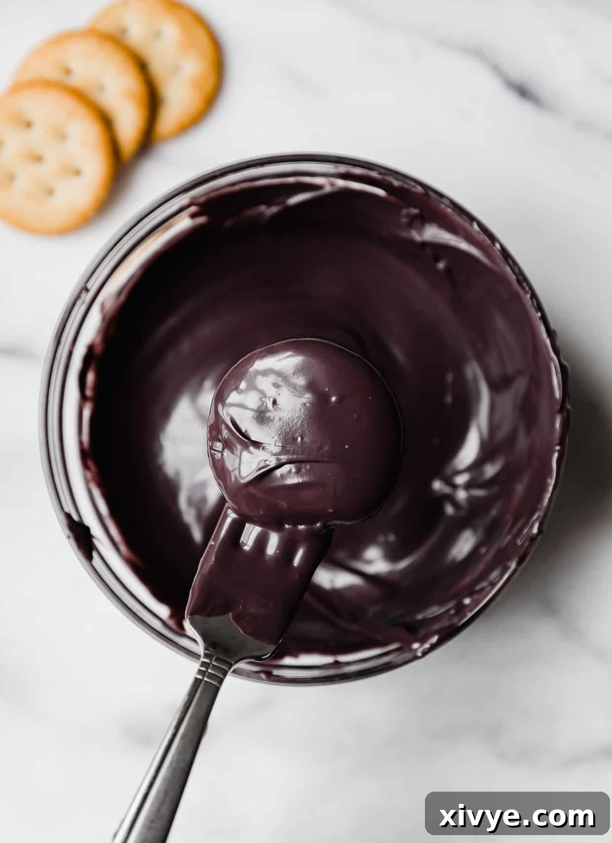 A ritz cracker dunked in black melting chocolate for making Halloween Crackers.