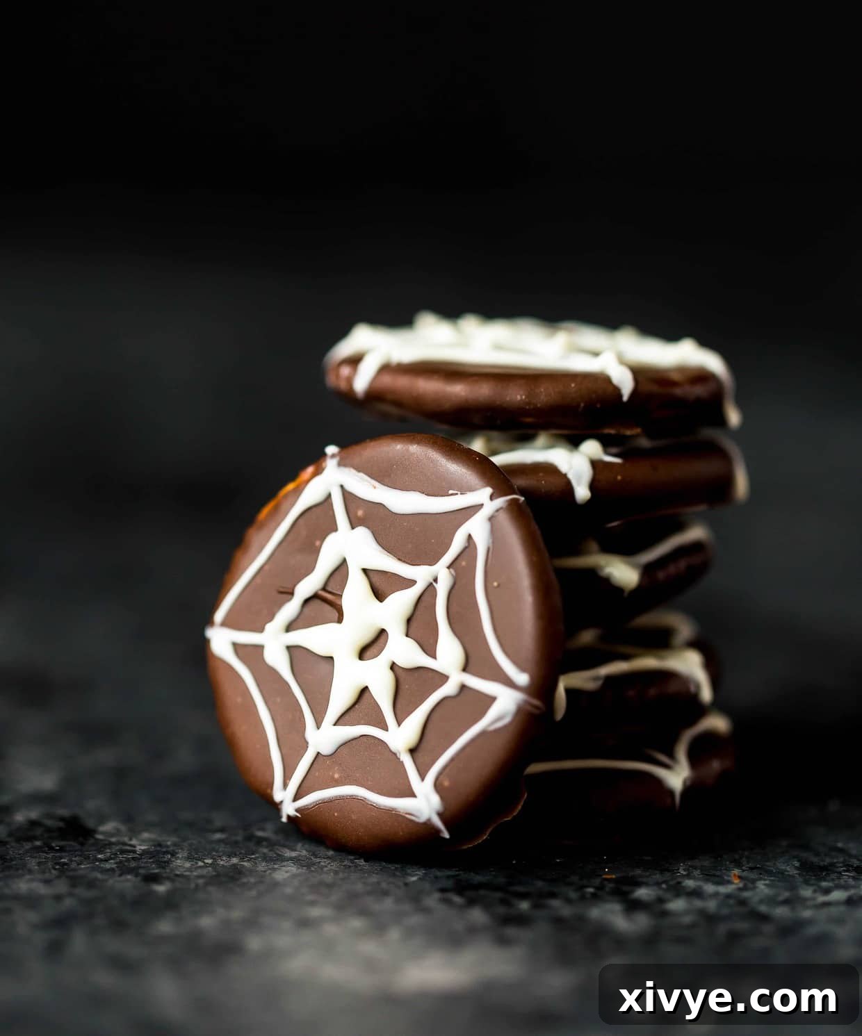 Chocolate covered ritz crackers featuring a white chocolate spider web design on top of cracker.
