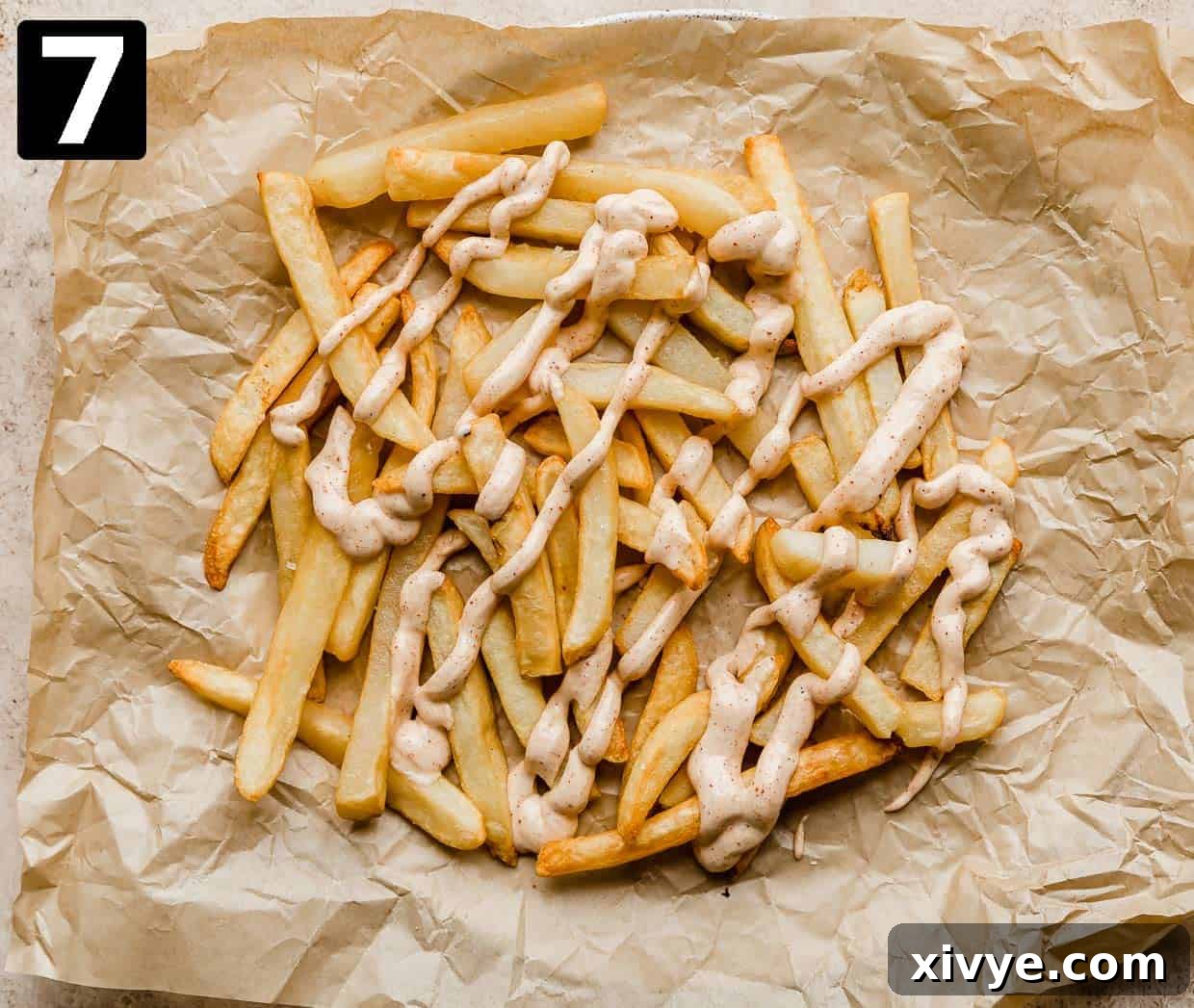 Golden Corn Sticks 6 Crispy French fries artfully drizzled with a creamy, zesty crema sauce, resting on tan parchment paper.