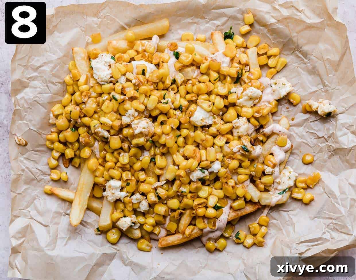 Golden Corn Sticks 7 Golden French fries generously topped with a vibrant Mexican Street Corn mixture, presented on parchment paper.