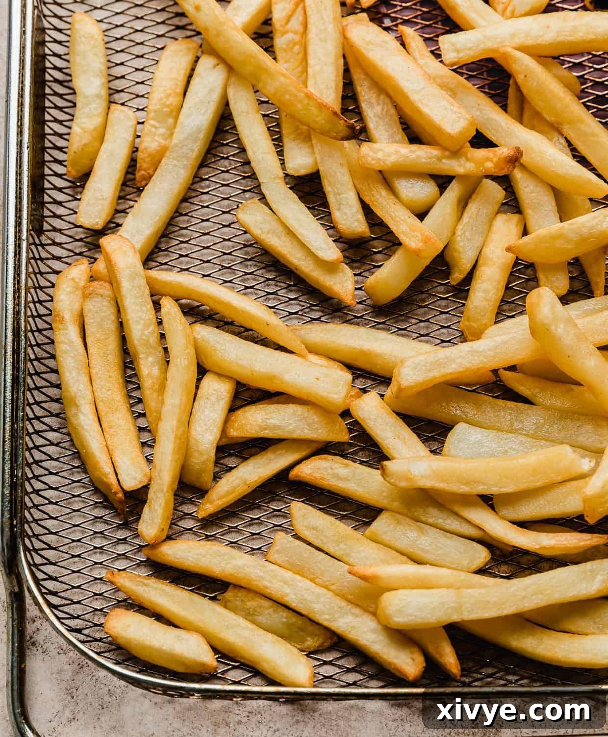 frozen French fries that were made in the air fryer, now golden and crispy on a metal air fryer basket.