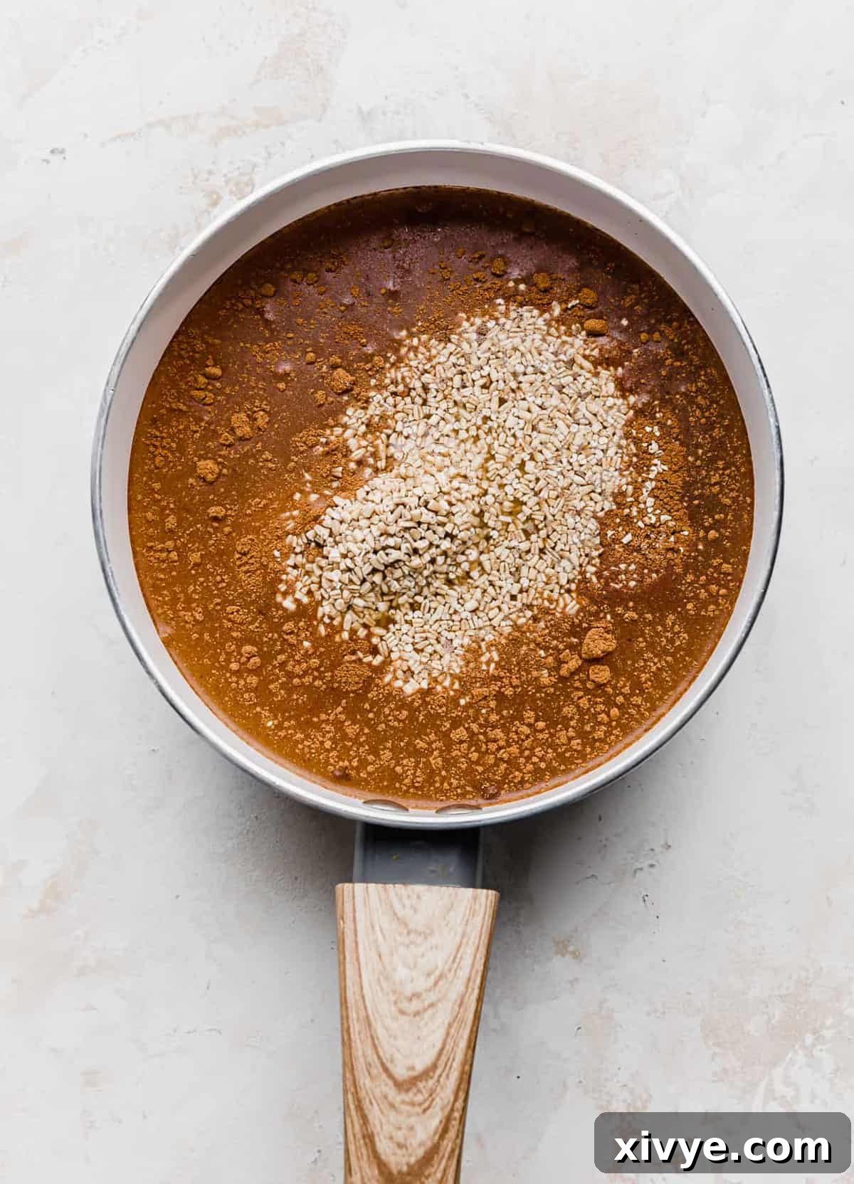 Spiced Pumpkin Steel Cut Oats 5 Raw steel cut oats in a white saucepan amongst a amber colored liquid.