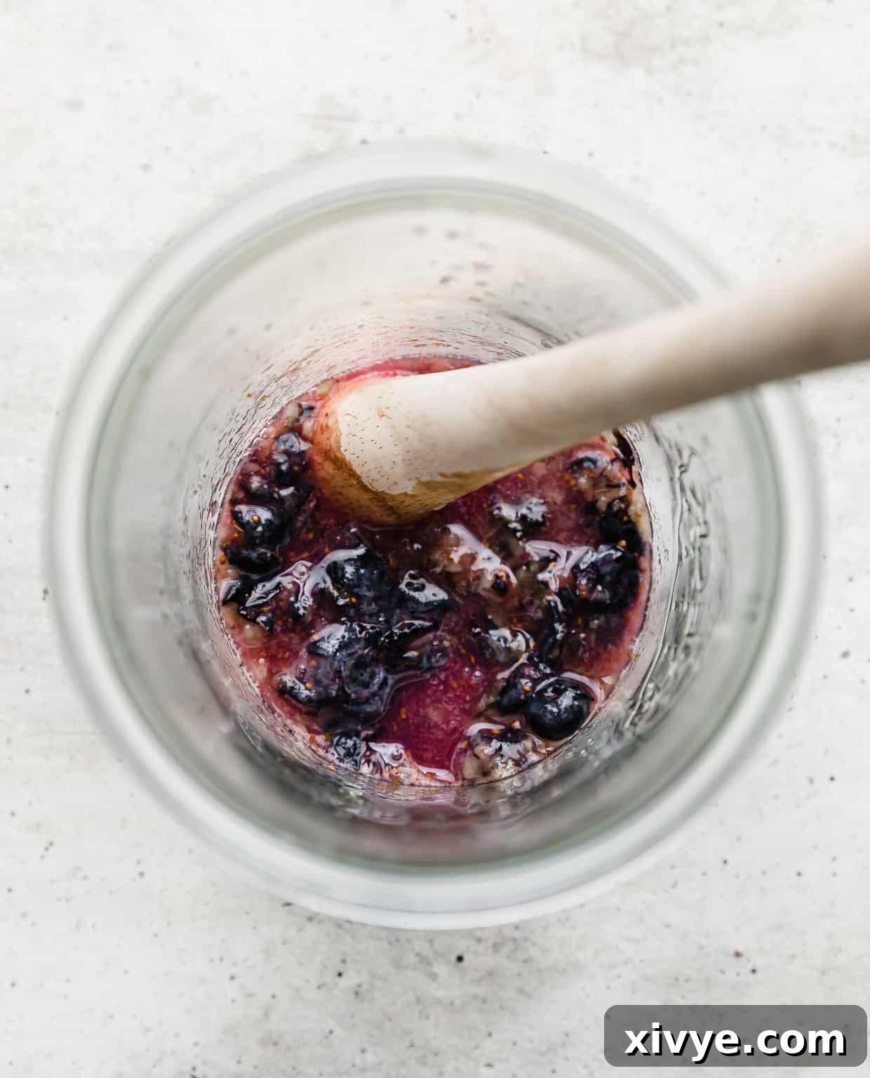 Smash blueberries and mint leaves in a glass jar, showing the juices being released.