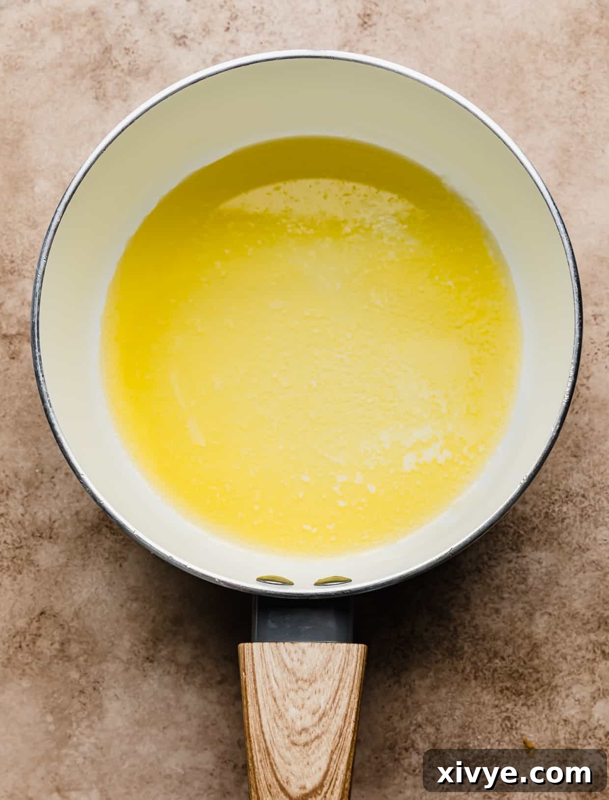 A white saucepan with melted butter in it, shimmering under the heat.