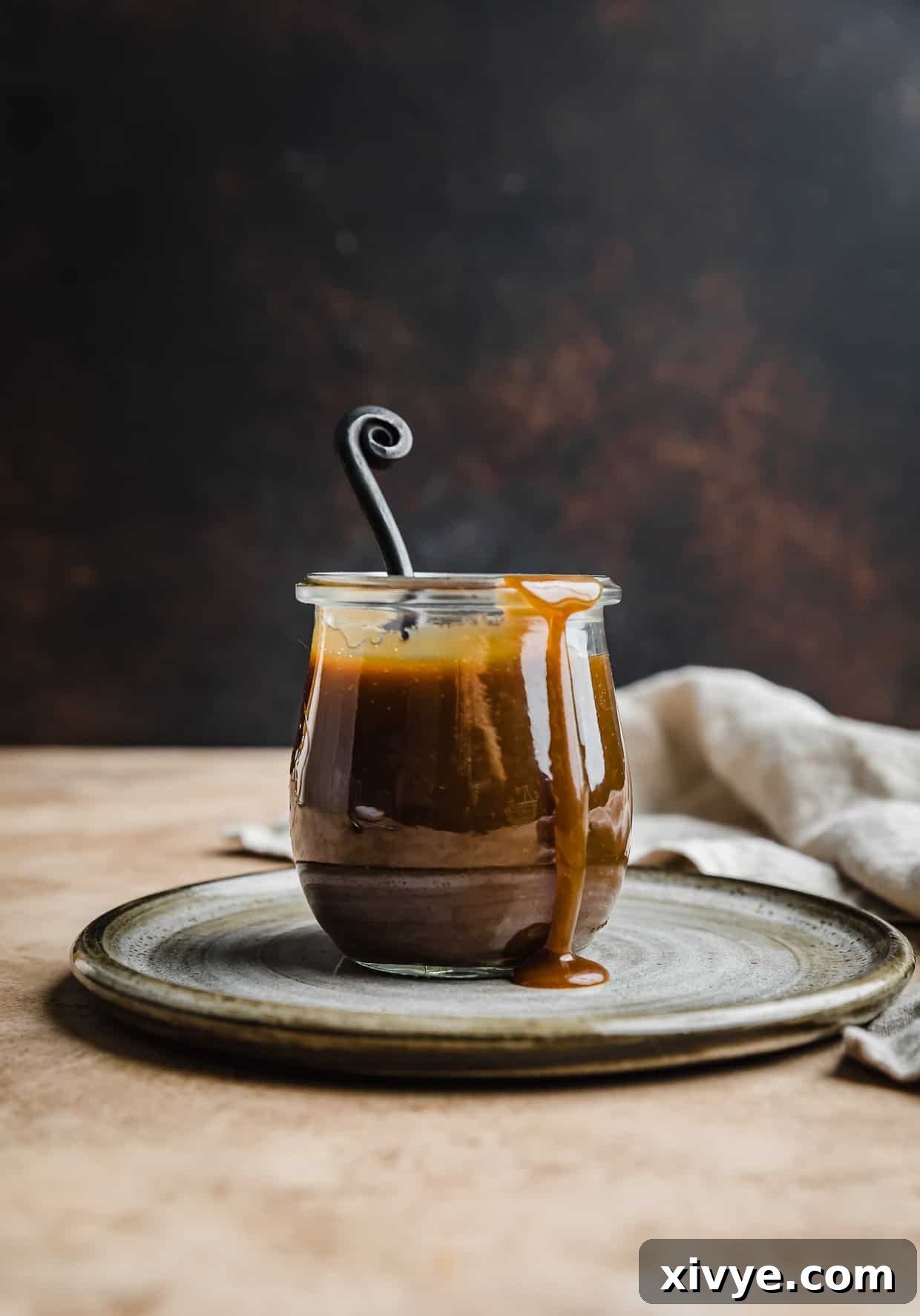 Homemade butterscotch recipe in a glass jar, beautifully presented against a warm brown background.