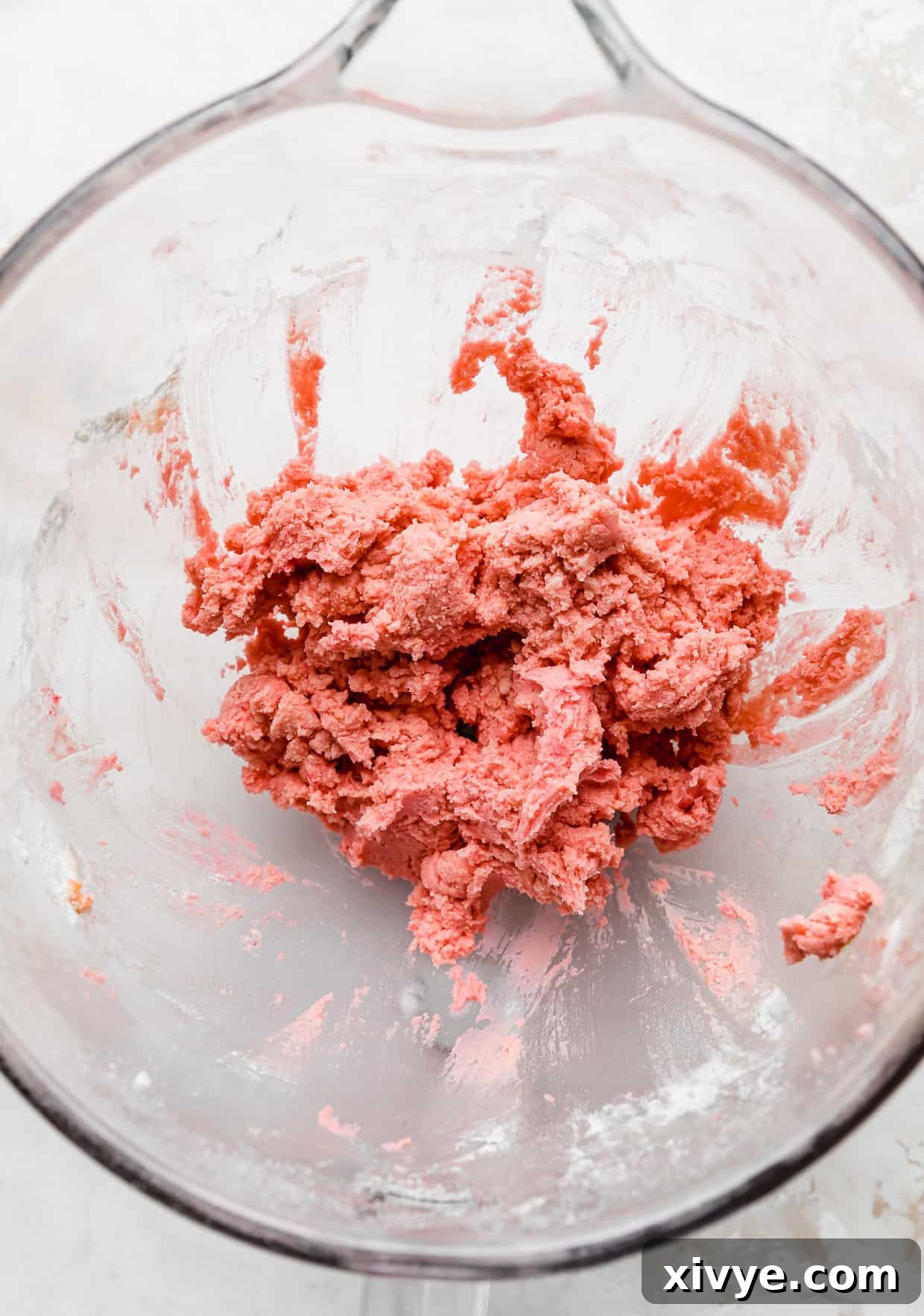Pink Velvet Cookie dough in a glass bowl on a white background.