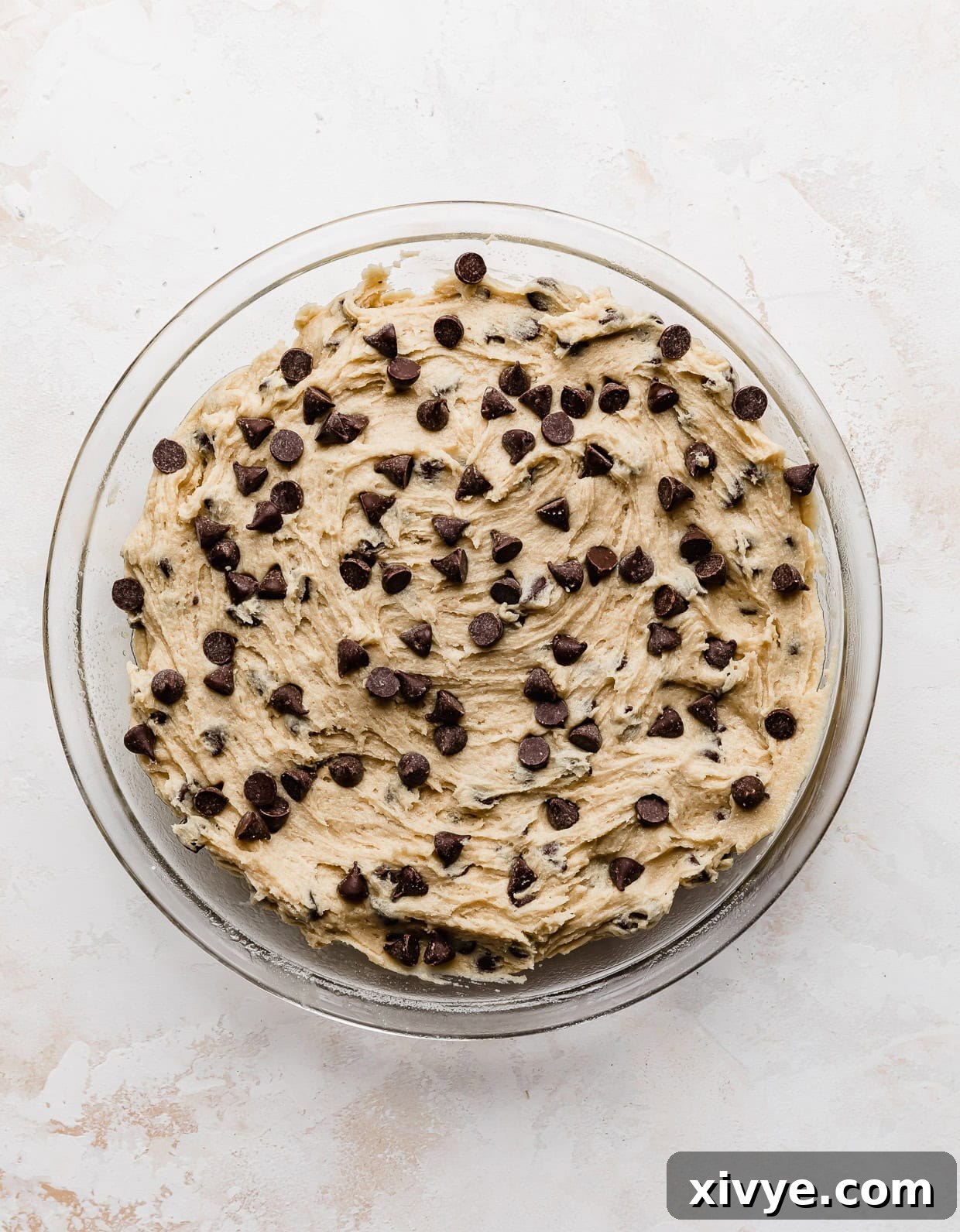 Ultimate Chocolate Chip Cookie Cake 7 Chocolate chips studded along the top of an unbaked chocolate chip cookie cake in a circular pie pan.