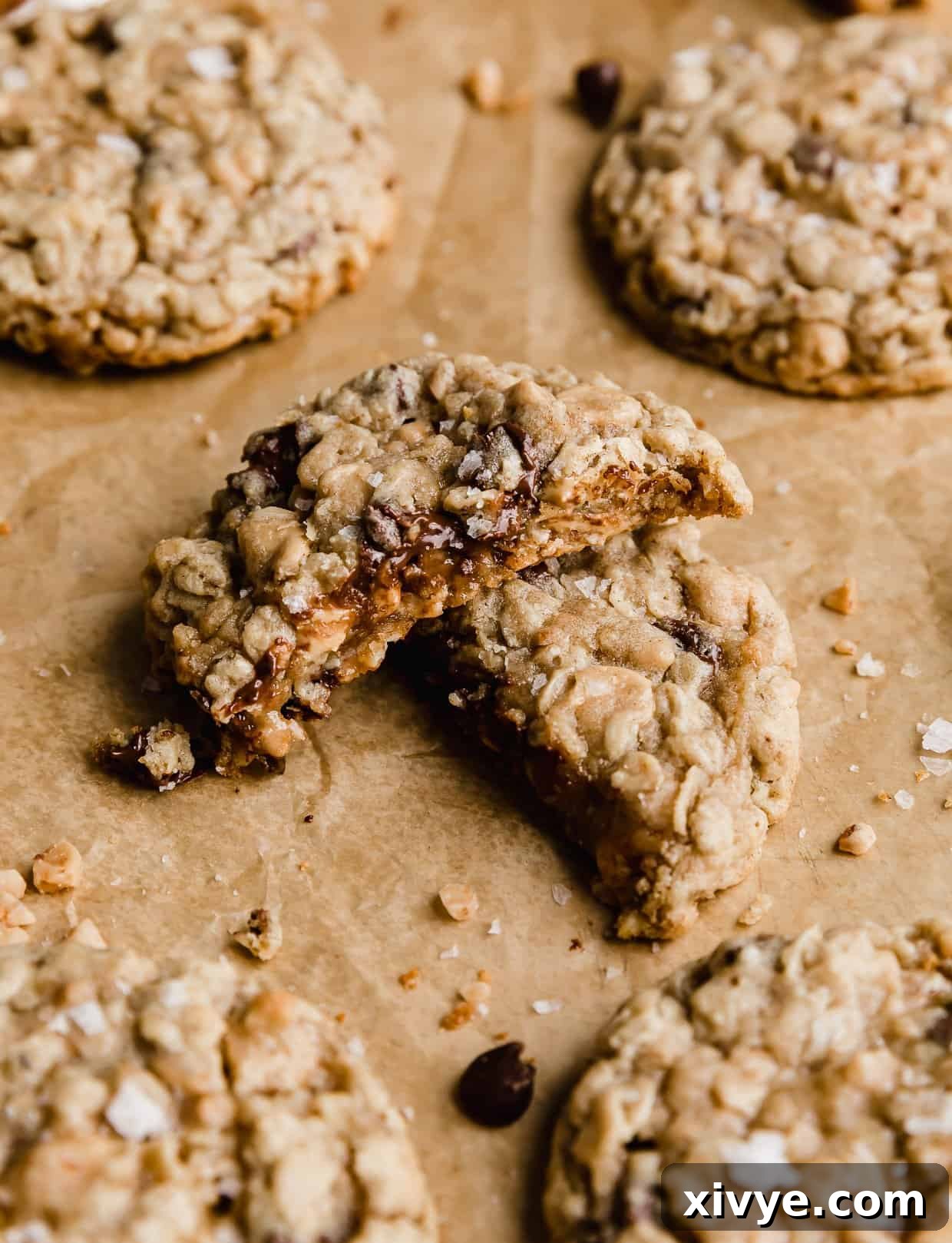 Crumbl Mom's recipe oatmeal cookie cut in half on a tan parchment paper. 