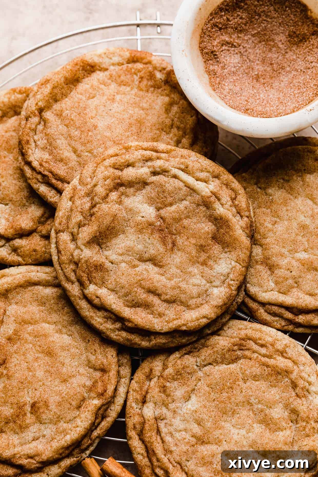 Your Ultimate Crumbl Snickerdoodle Copycat Recipe 9 A pile of snickerdoodle crumbl copycat cookies on a cooling rack.