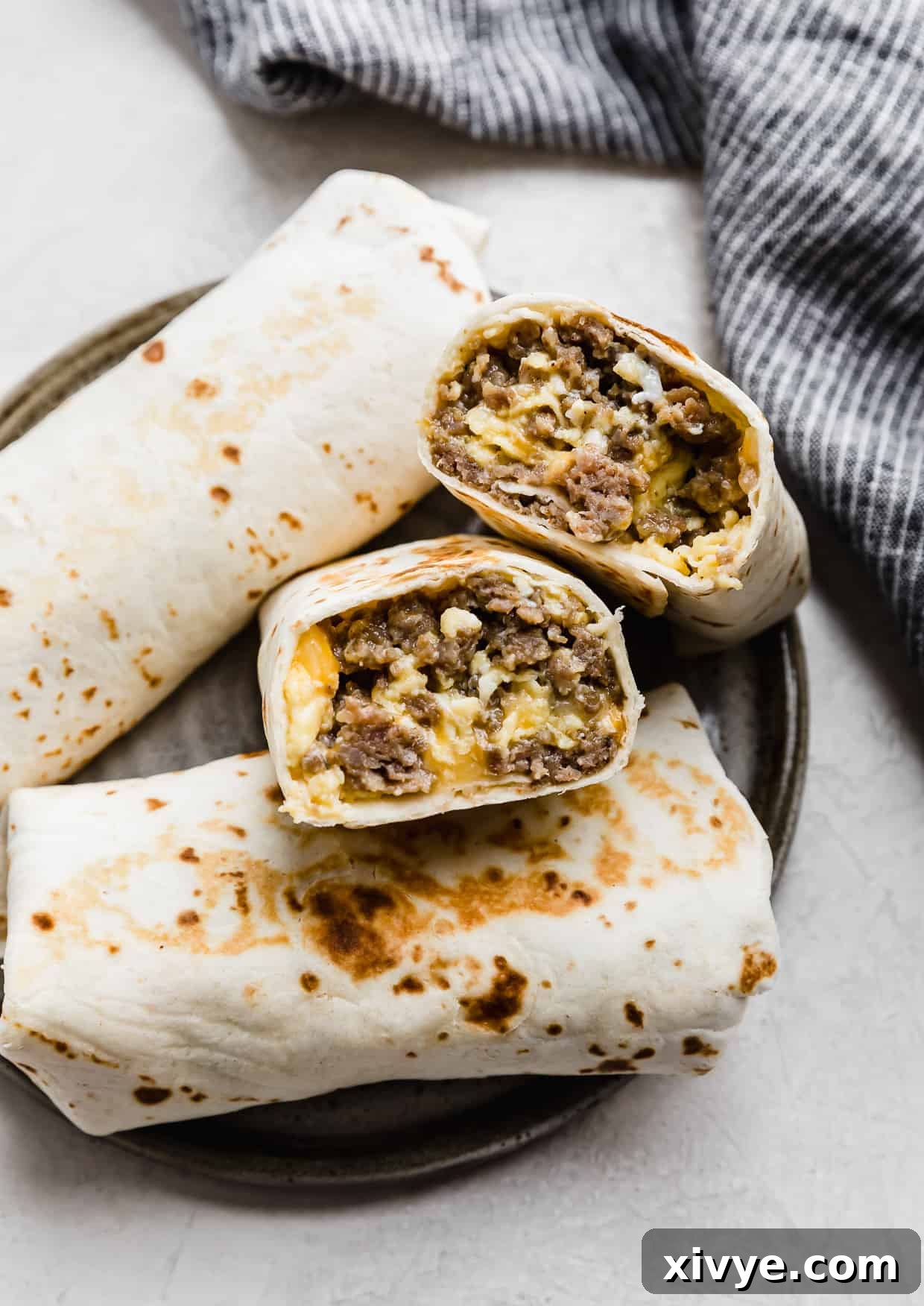 A perfectly cooked Jimmy Dean Breakfast Burrito, sliced in half to reveal the savory filling of sausage, eggs, and cheese, resting on a rustic gray plate.