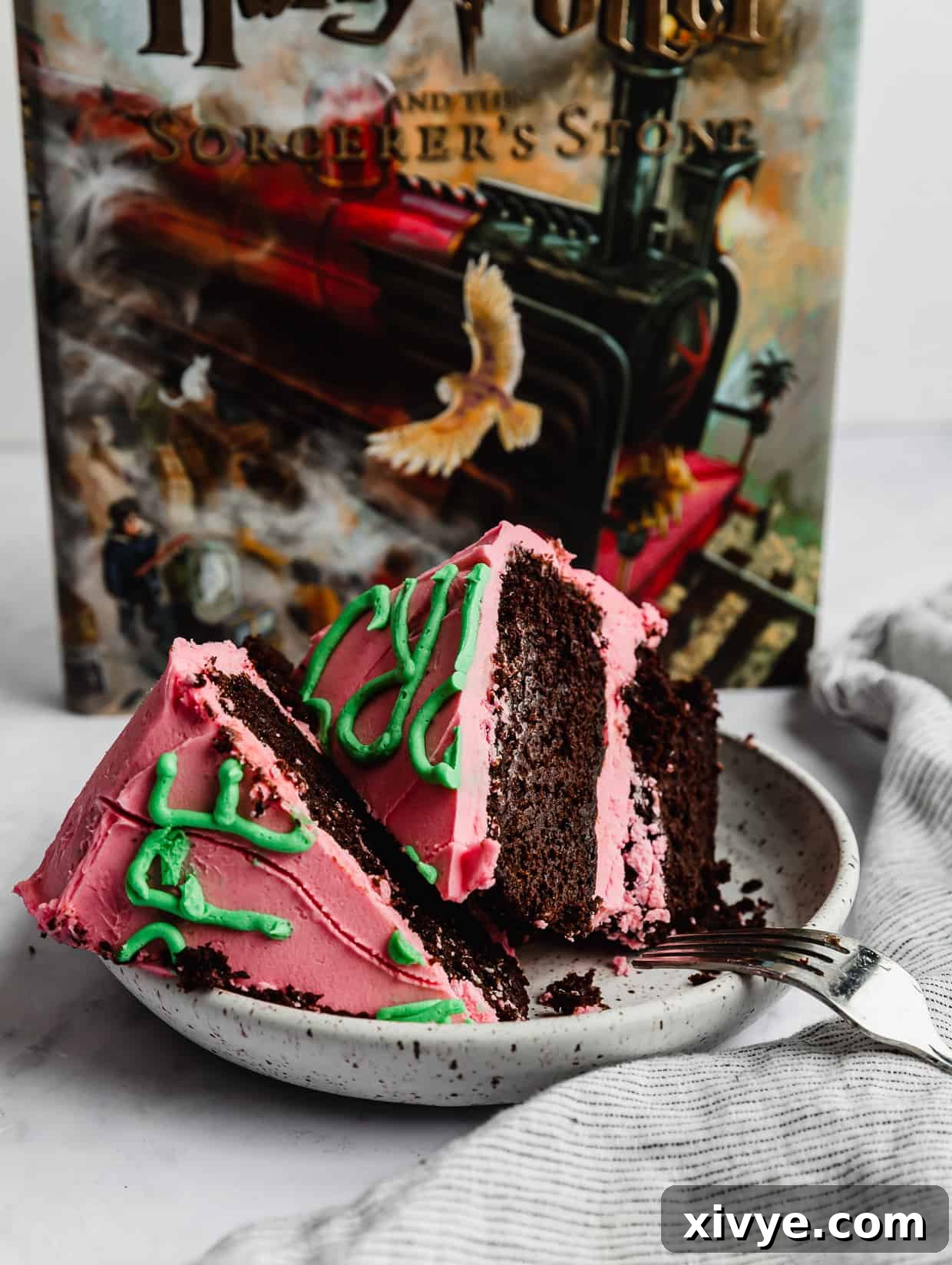 Spellbinding Harry Potter Birthday Delight 12 Harry Potters Birthday Cake decorated in pink icing and green lettering, cut into wedges on a white plate with a Harry Potter book in the background.