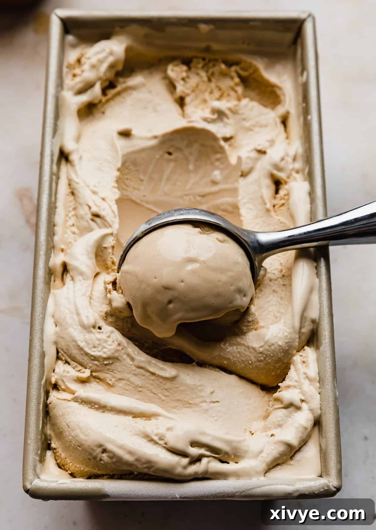 Velvet Butterscotch Indulgence 7 An ice cream scooper scooping out Butterscotch Ice Cream from a rectangle bread pan.