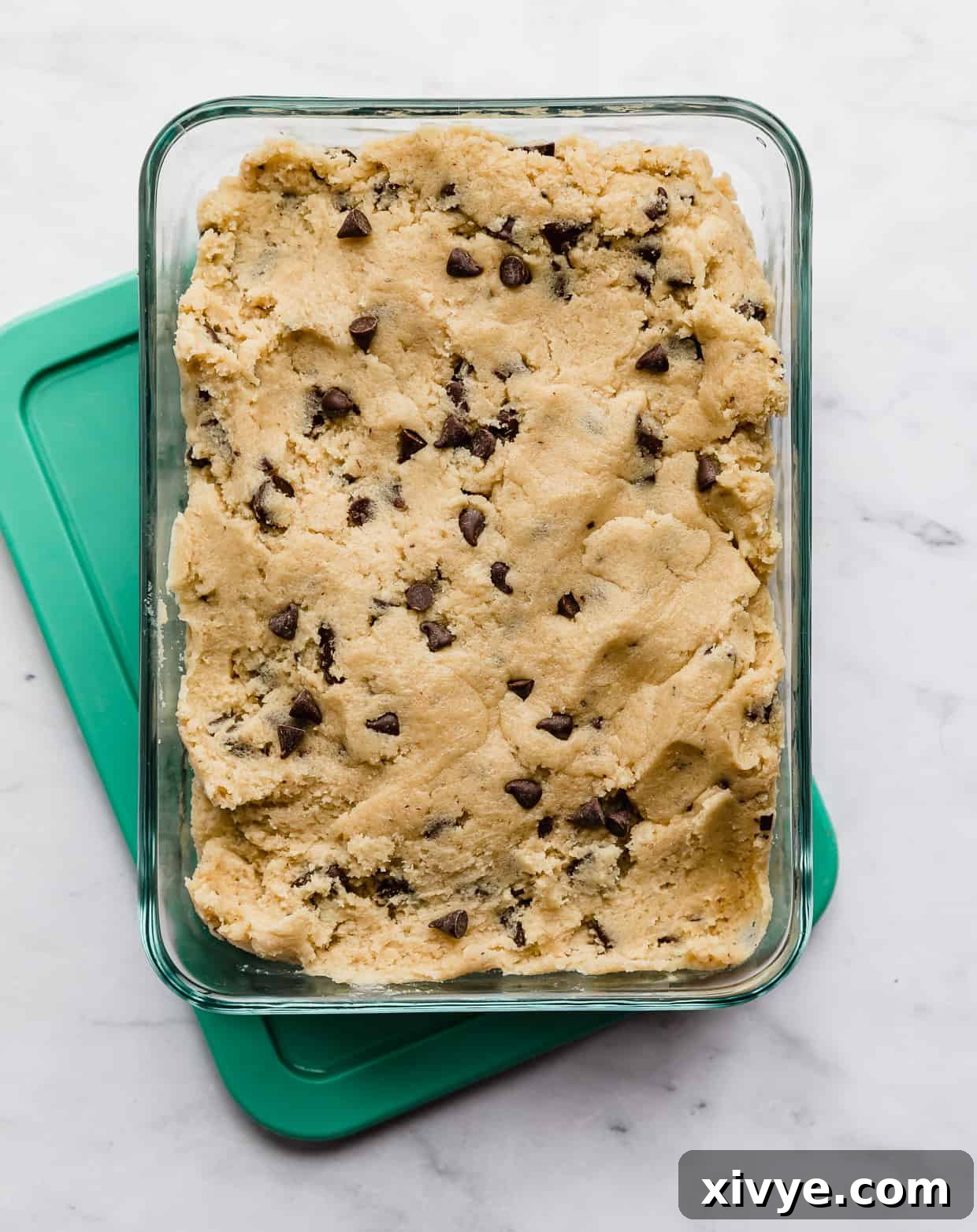 Bake Later: Freeze Cookie Dough for Future Treats 3 Freshly prepared chocolate chip cookie dough resting in a clear rectangular glass storage container, ready for chilling.