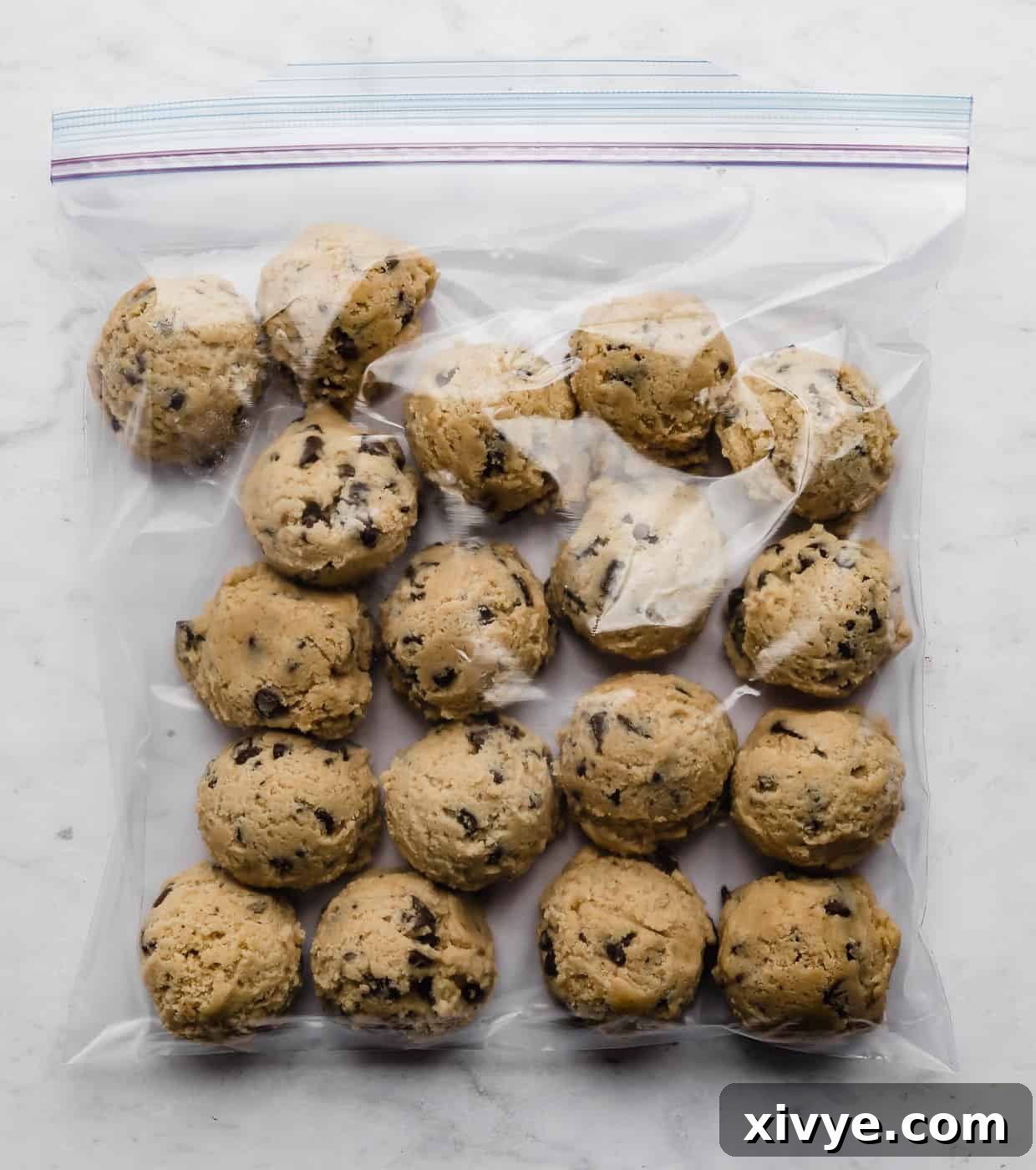 Bake Later: Freeze Cookie Dough for Future Treats 7 Close-up of frozen chocolate chip cookie dough balls neatly packed in a clear Ziploc bag, set against a clean white background.