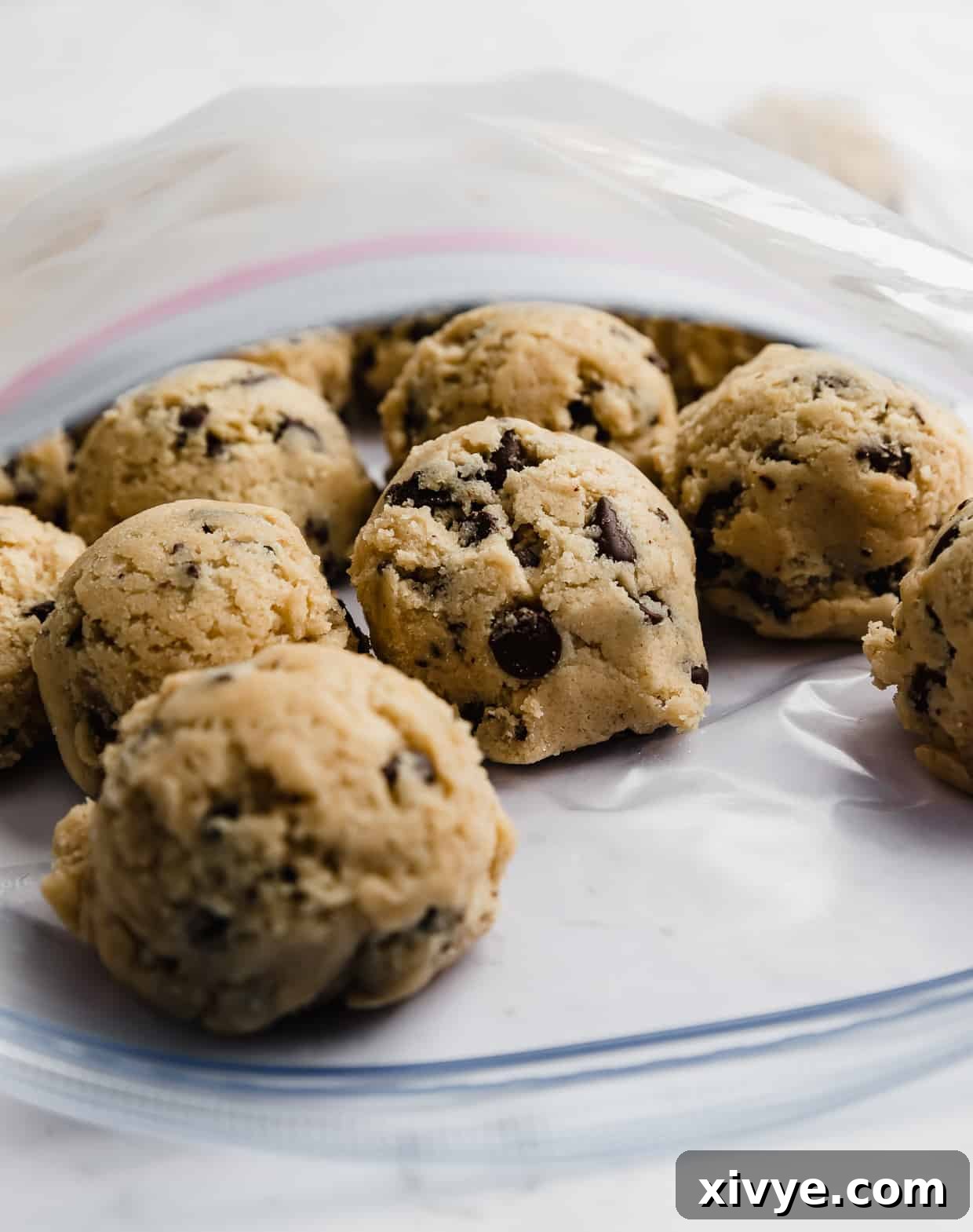 Bake Later: Freeze Cookie Dough for Future Treats 8 Detailed shot of frozen chocolate chip cookie dough balls neatly sealed in a Ziploc bag, ready for freezer storage.