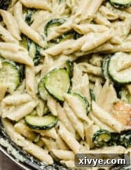 A close up photo of Pasta with Zucchini and Ricotta in a black pot, showing the creamy texture and fresh basil garnish.