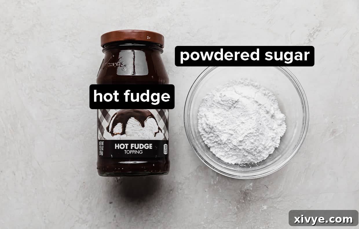 A jar of hot fudge sauce and a bowl of powdered sugar on a gray background.