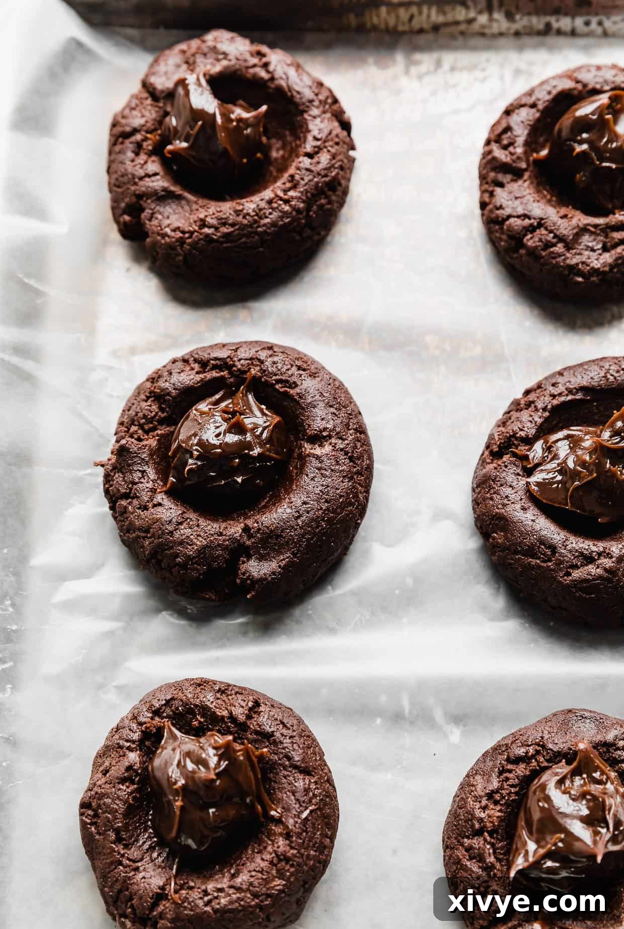 Hot fudge sauce carefully placed in the center of chocolate cookie dough balls, ready to be sealed.