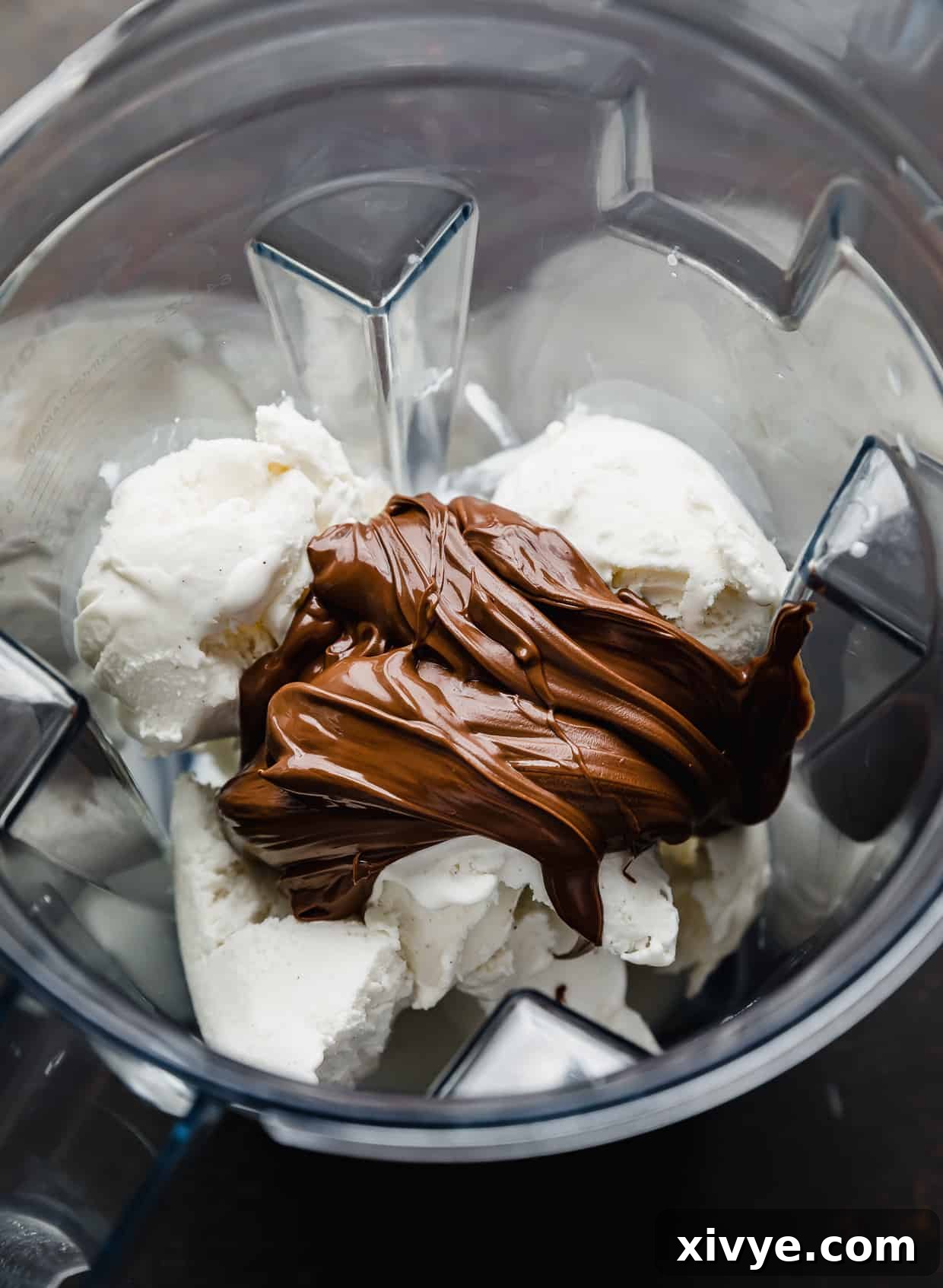 Vanilla ice cream and Nutella being added to a blender, ready to be transformed into a creamy milkshake.
