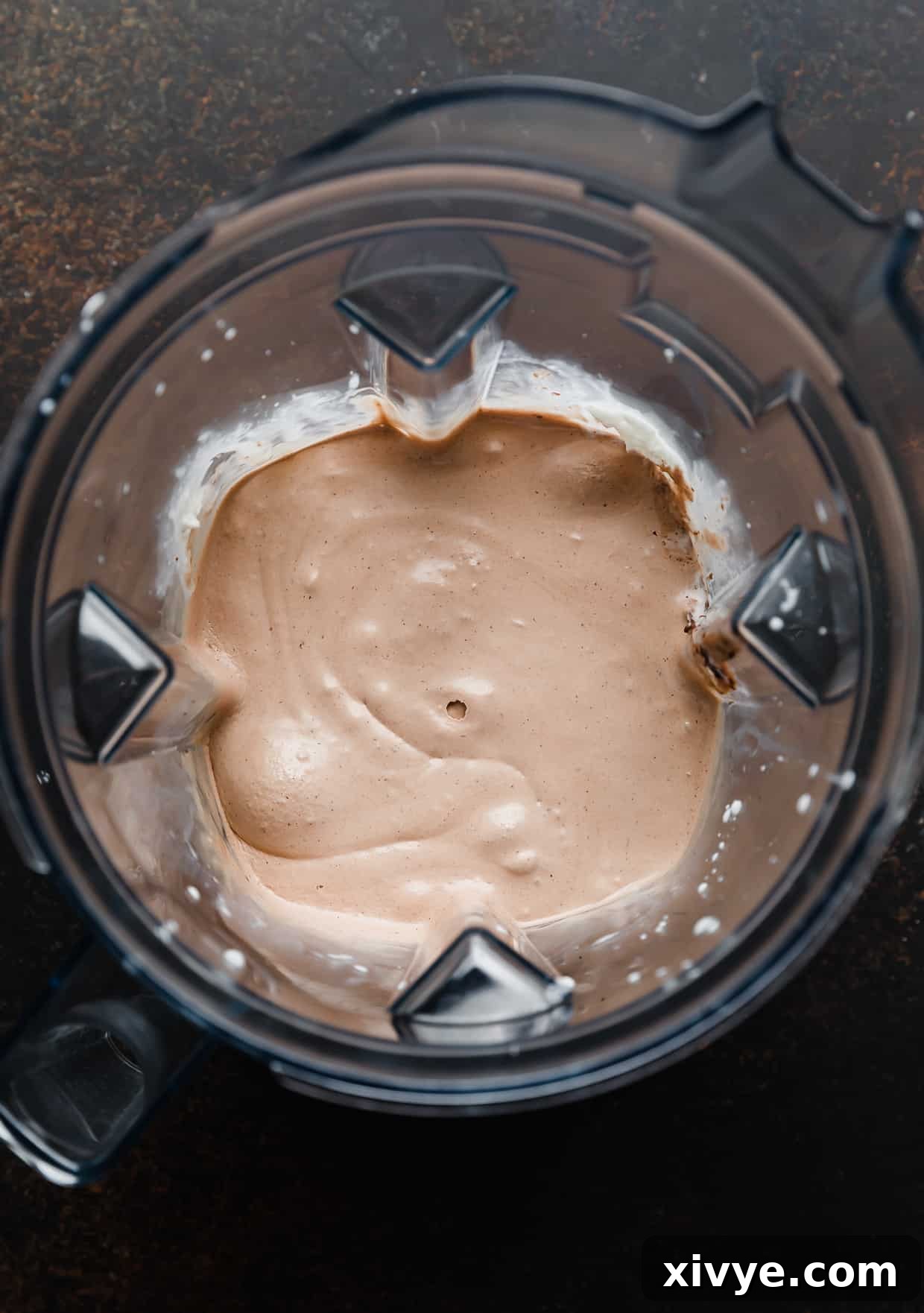 A light brown Nutella Milkshake, perfectly blended and swirling smoothly within the blender pitcher, awaiting transfer to a glass.
